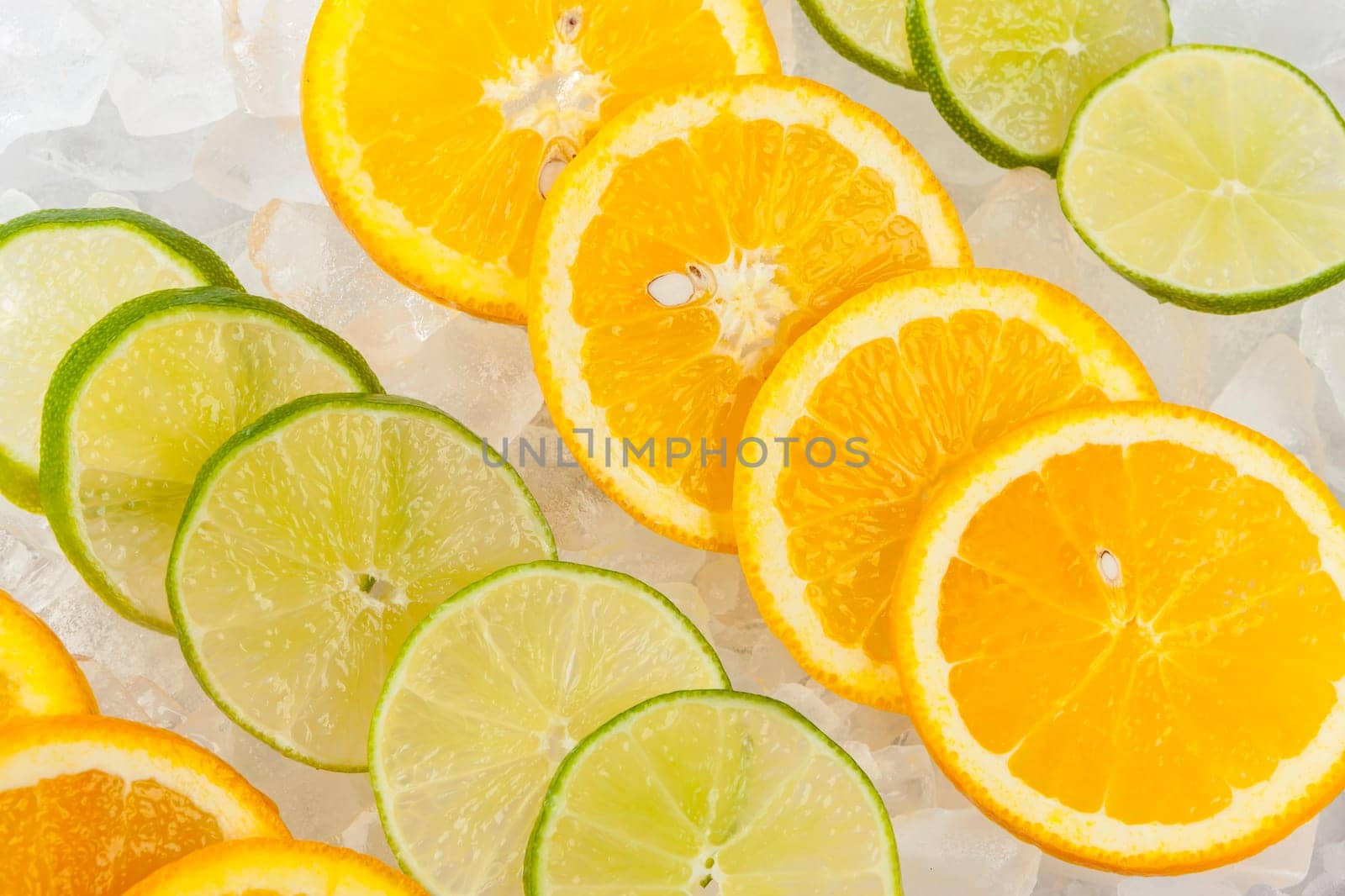 Rows of orange and lime slices laying on ice.