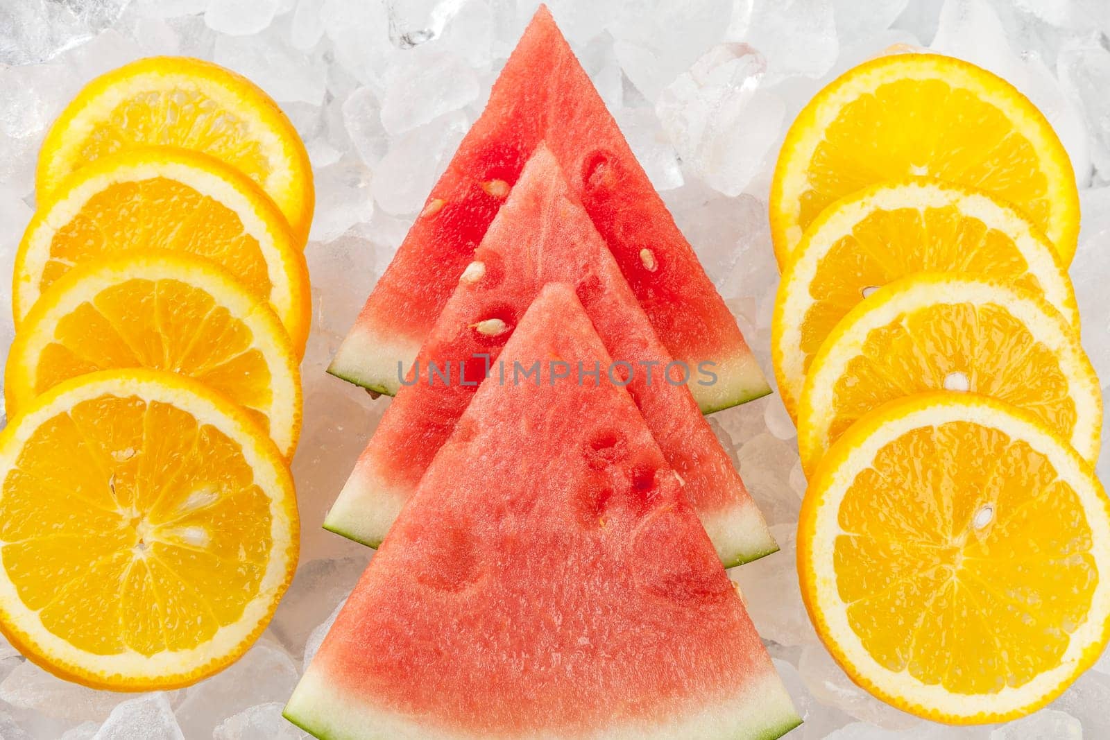 Rows of orange slices and watermelon wedges stacked up on ice.