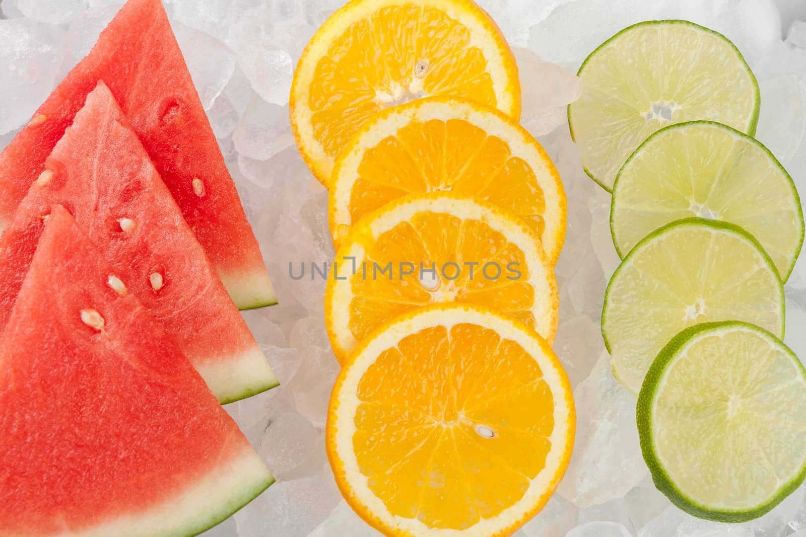 Watermelon, orange, and lime slices lined up on ice.