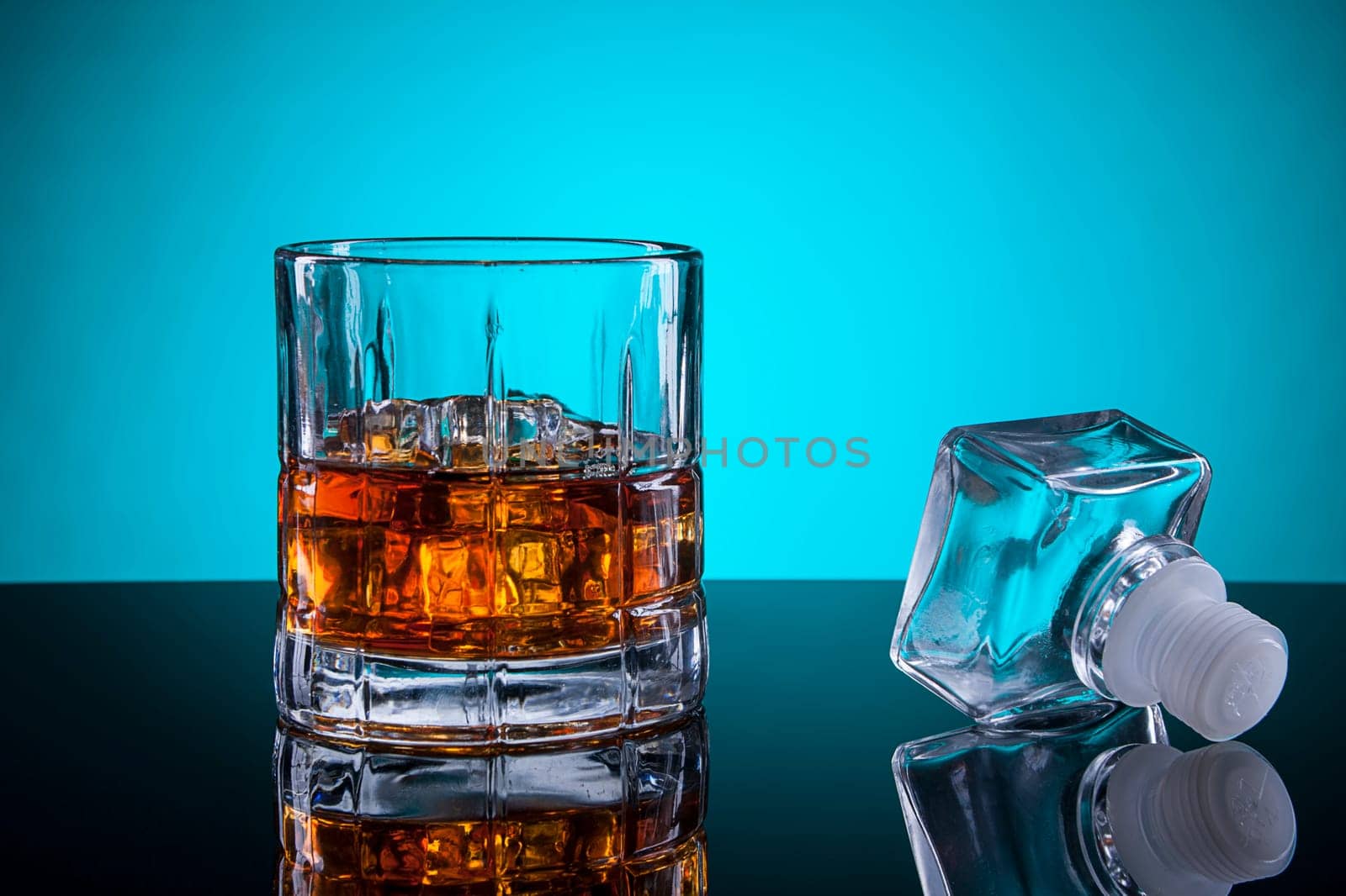 A close up of a glass of liquor with the bottle stopper.