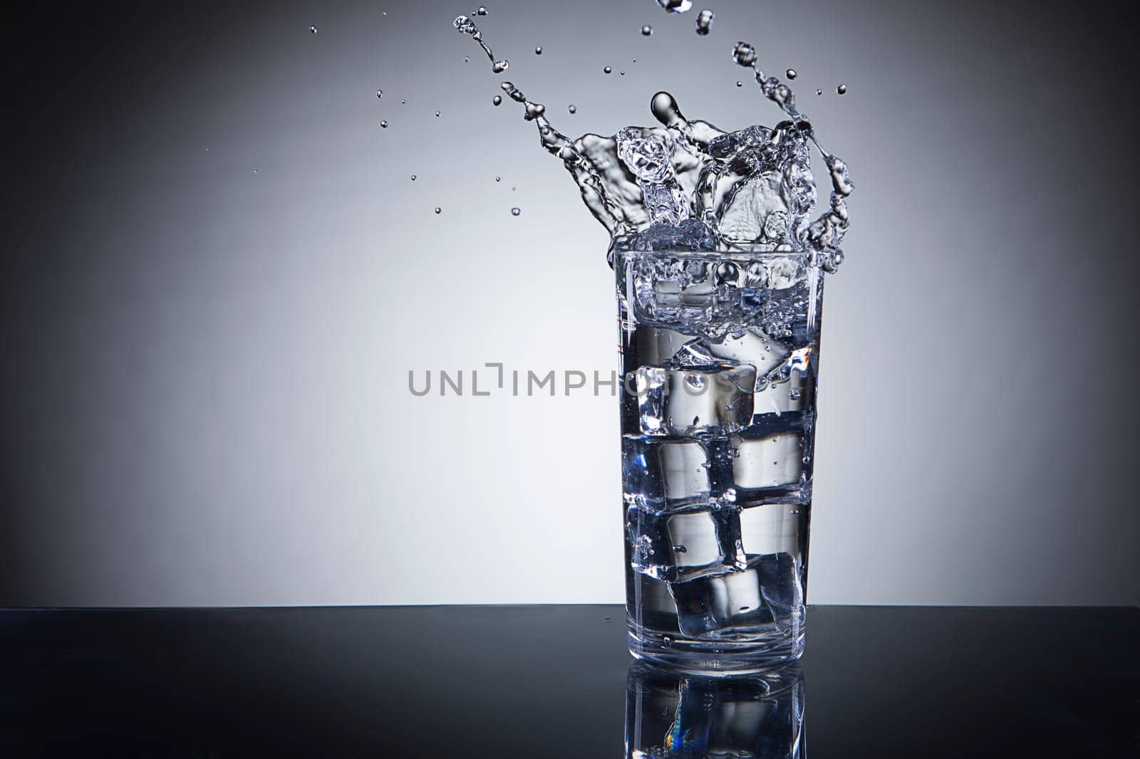 Ice being dropped into a glass of water making a splash.