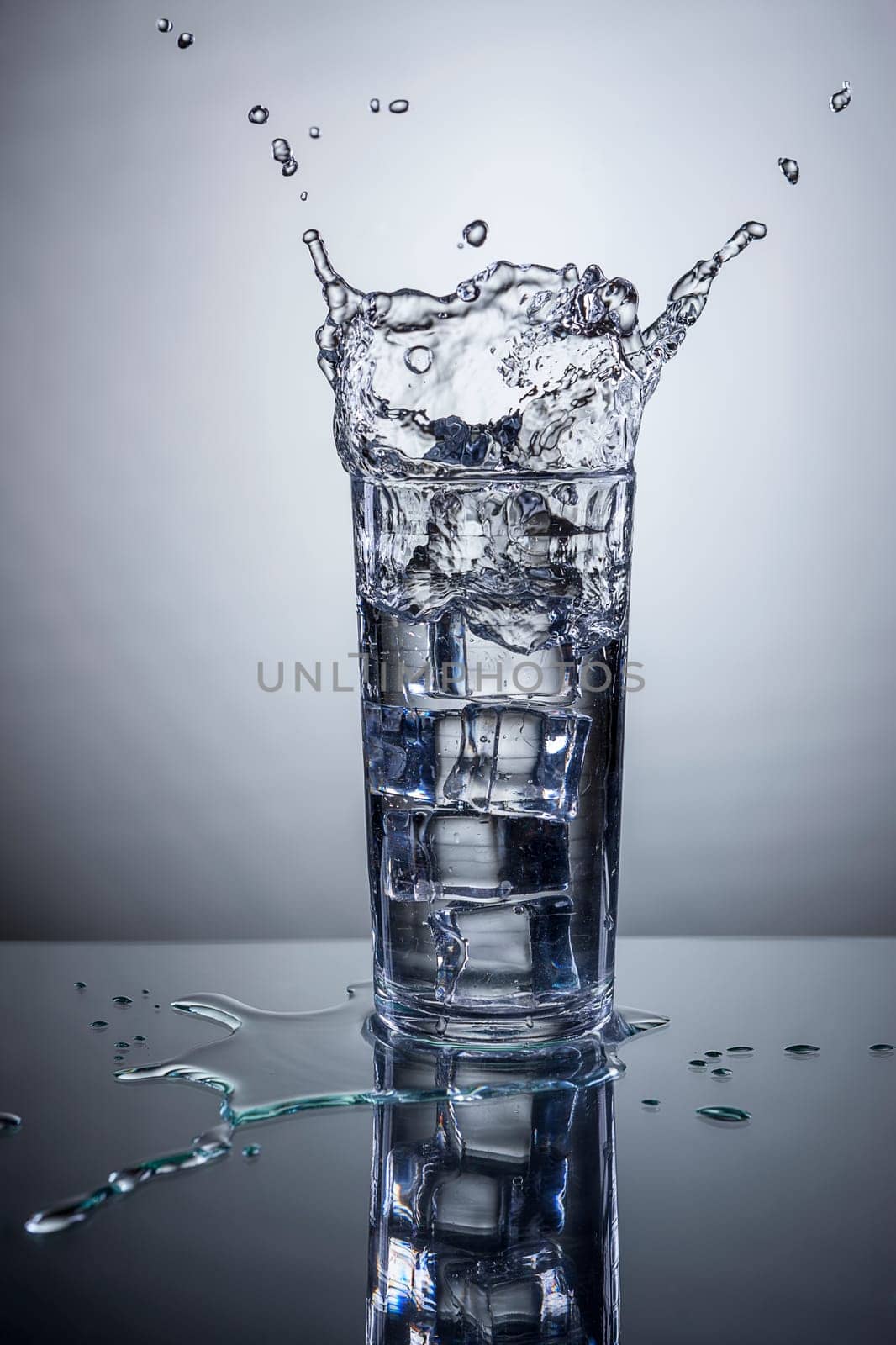 Ice being dropped into a glass of water making a splash.