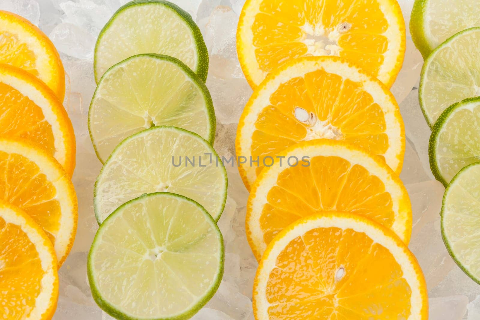 Rows of orange and lime slices laying on ice.