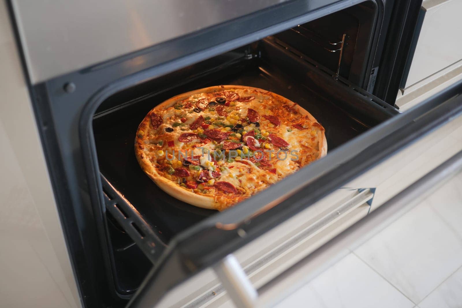 A delicious pizza is baking in an oven, with toppings visible inside.