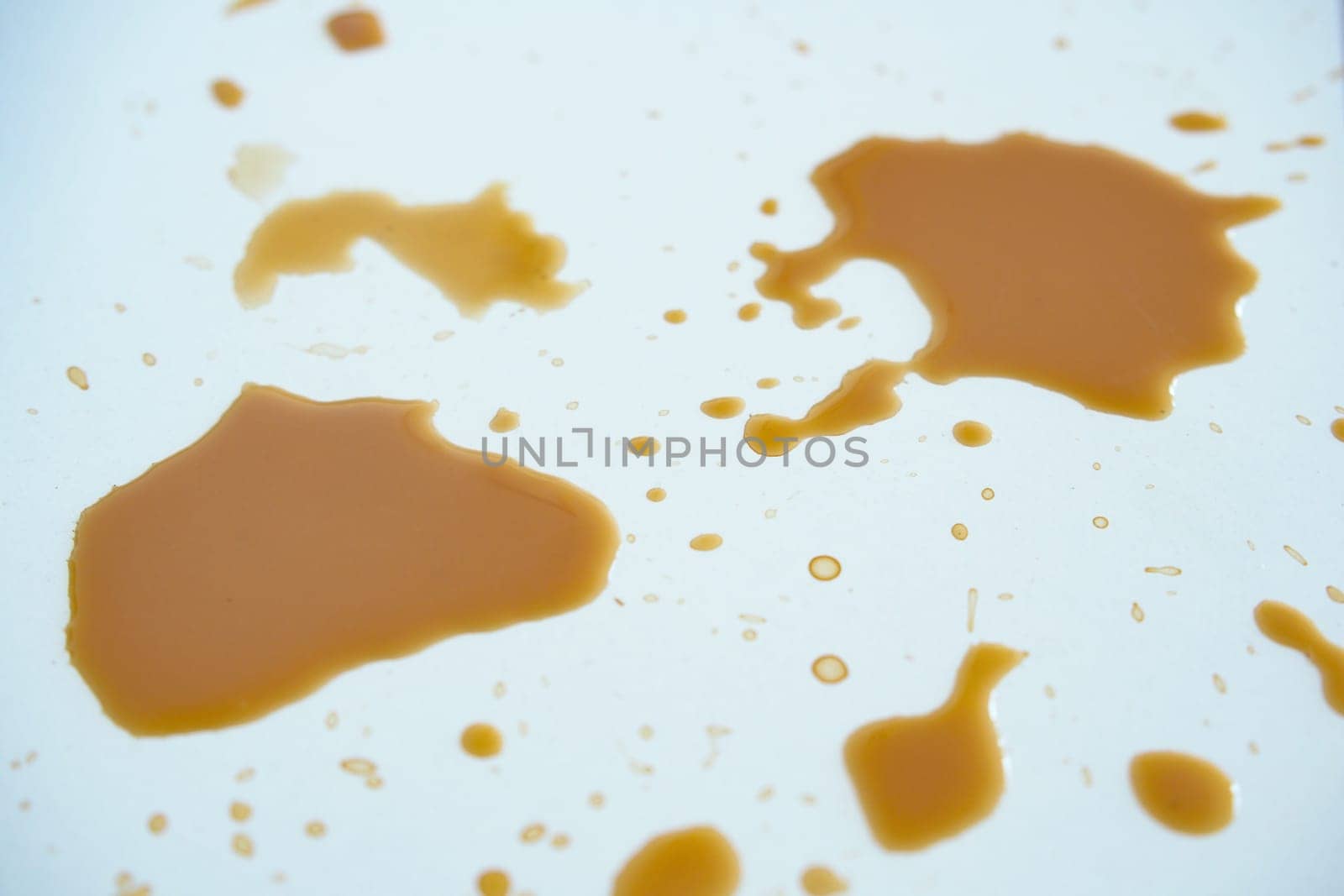 Spilled coffee forms interesting shapes on a light background.