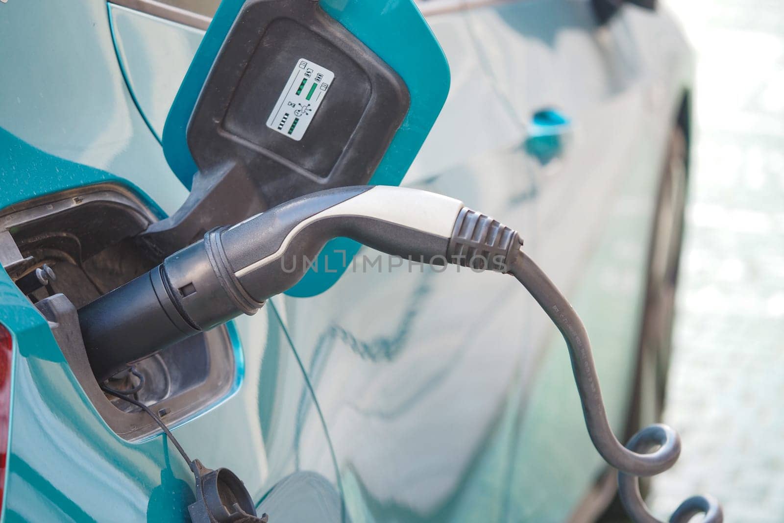 An electric vehicle is being charged at a public station outside.