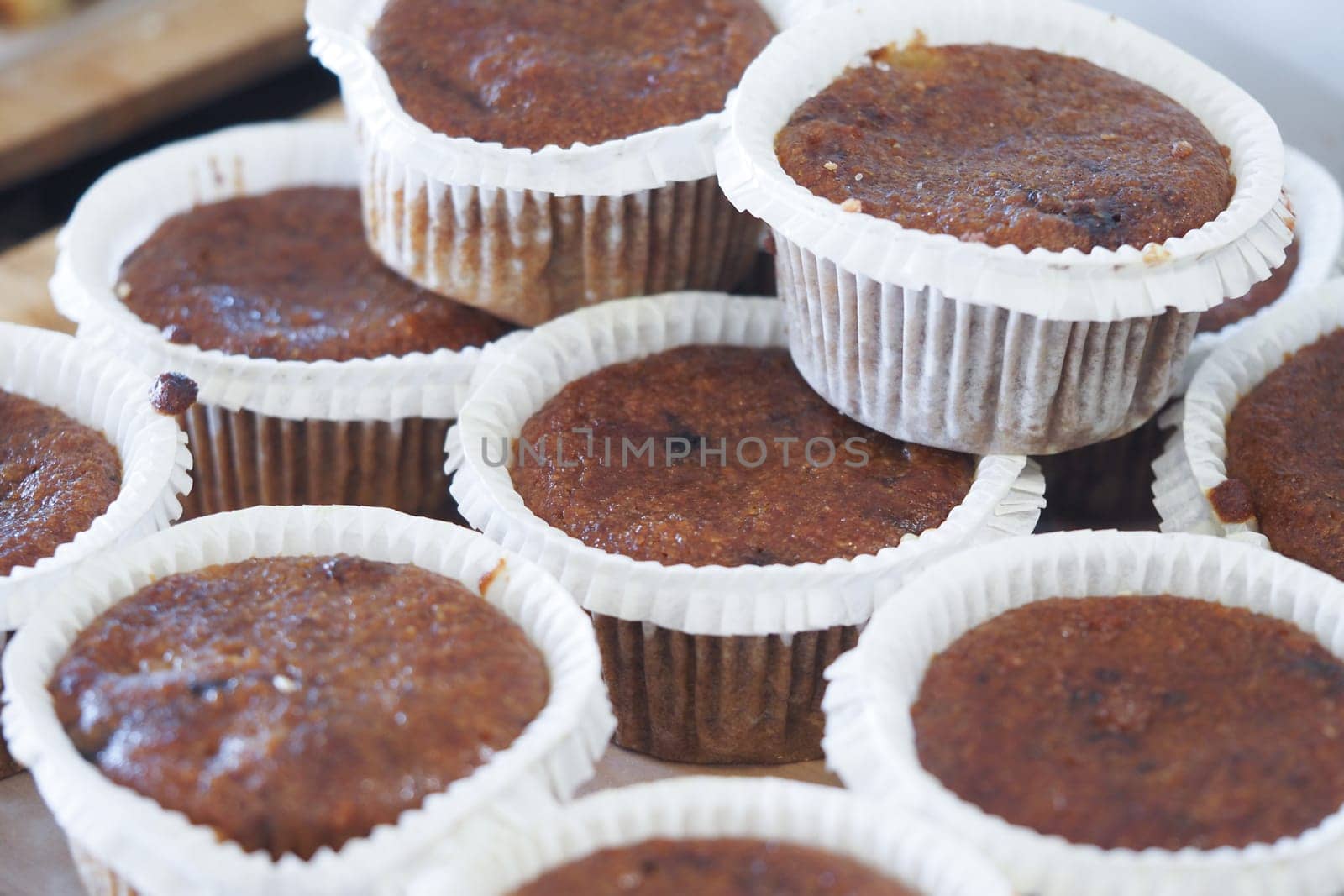 Delicious muffins are stacked together in cupcake liners for sale.