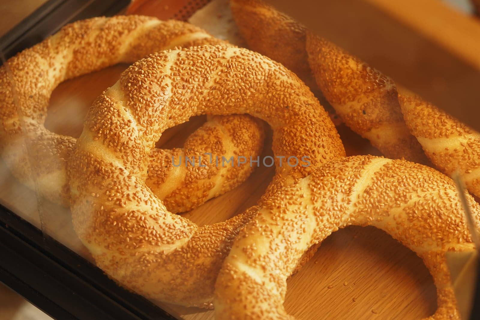 Warm, golden bread with sesame seeds rests in a wooden display case.