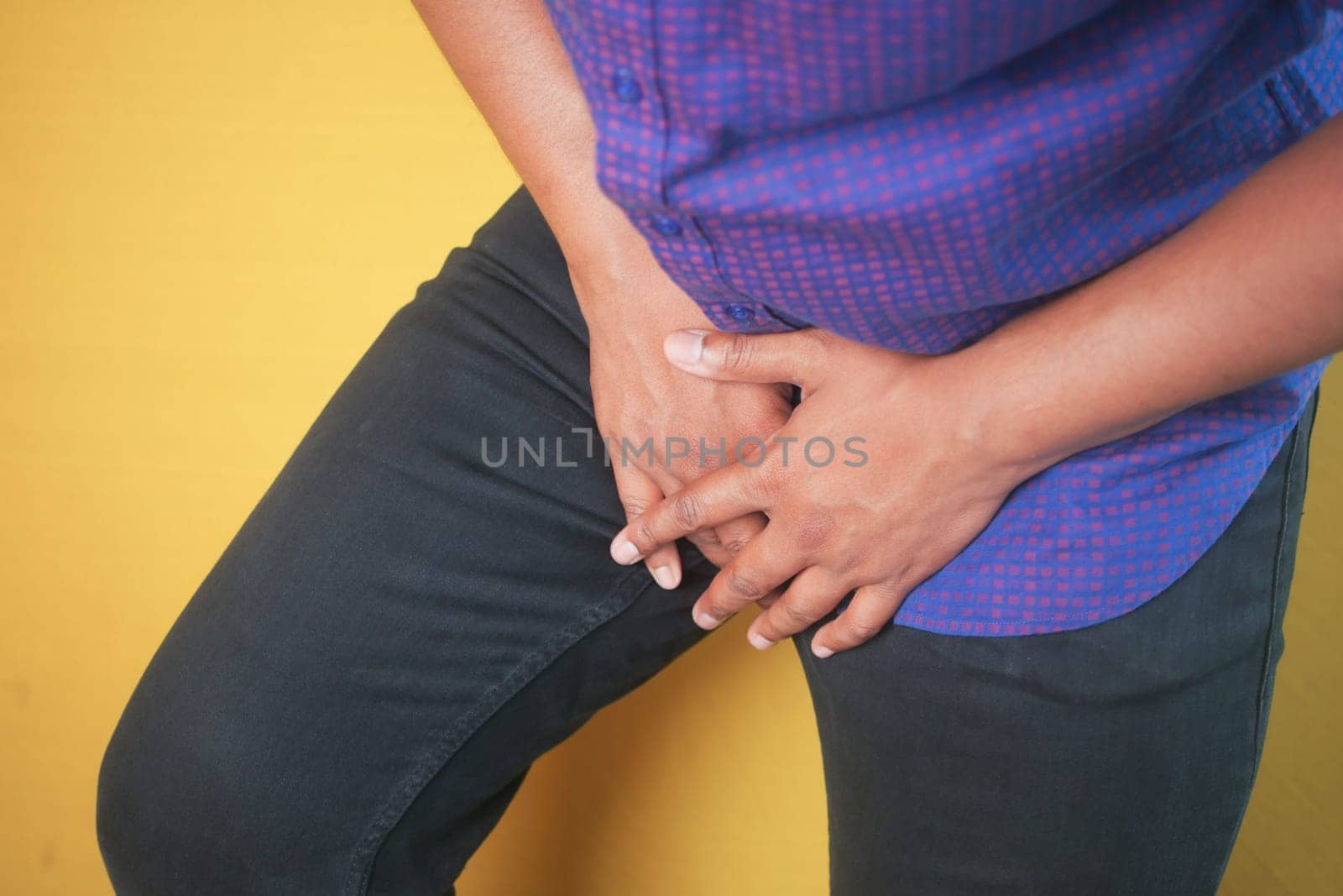 A man clasps his hands over his groin area as he stands alone.