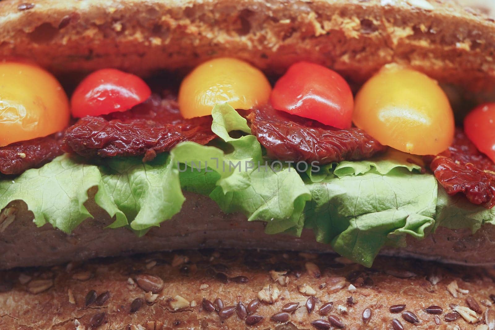 Vibrant vegetable toppings on a hearty sandwich against wood.