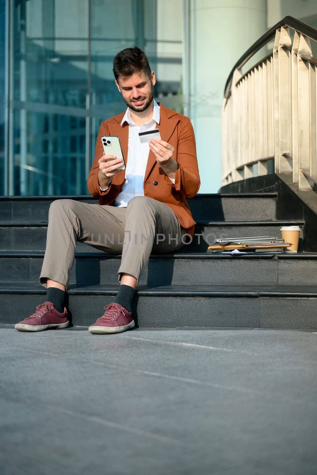 Businessman holding smartphone and credit card. Online banking and digital transactions concept.