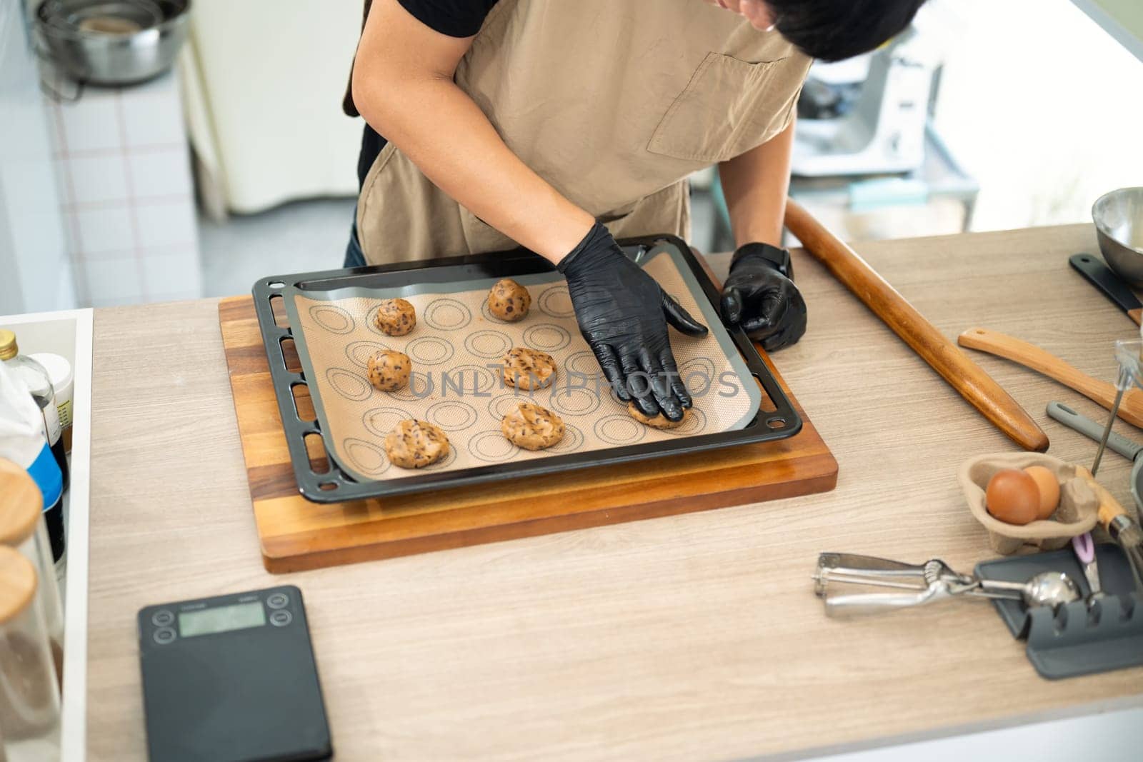 Baker preparing chocolate chip cookie dough on a baking tray.