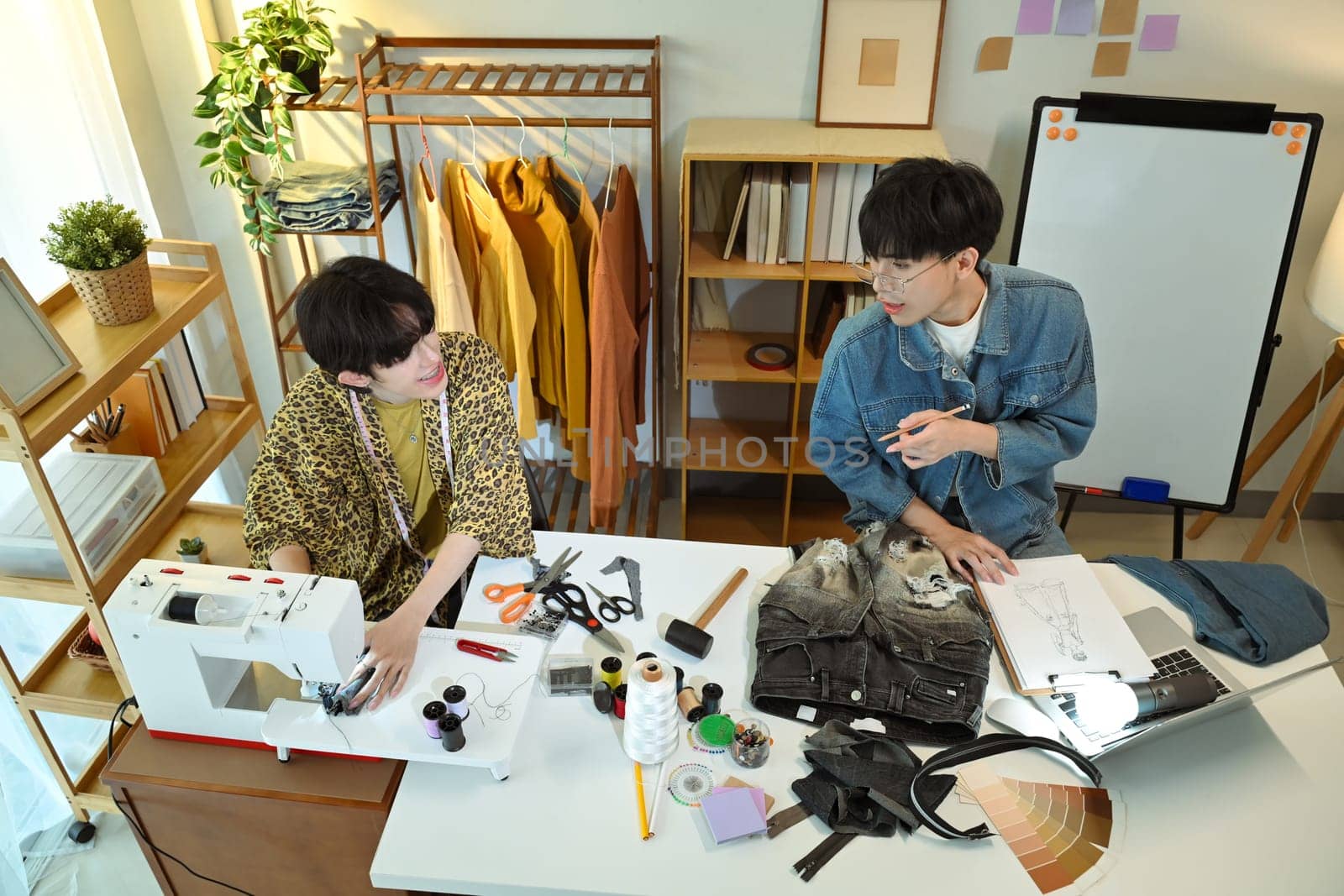 Two designers discussing ideas for a clothing project in a creative studio.