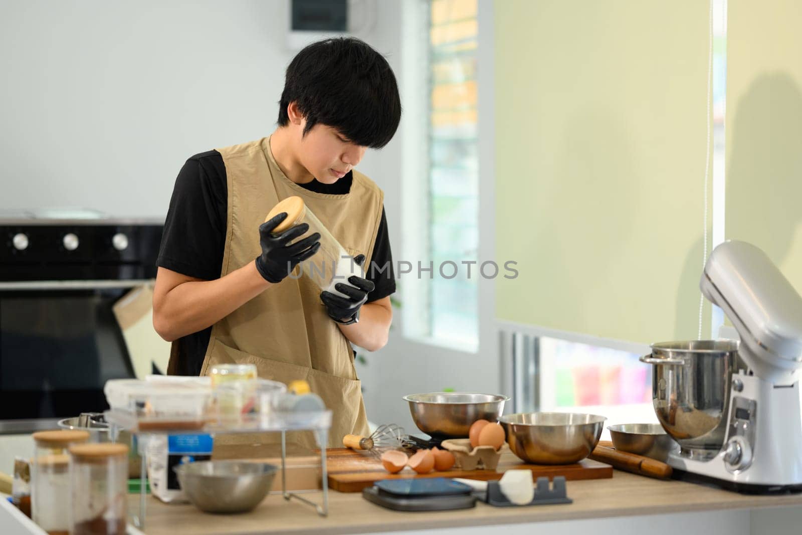 Young baker wearing gloves preparing ingredients for cookie dough.