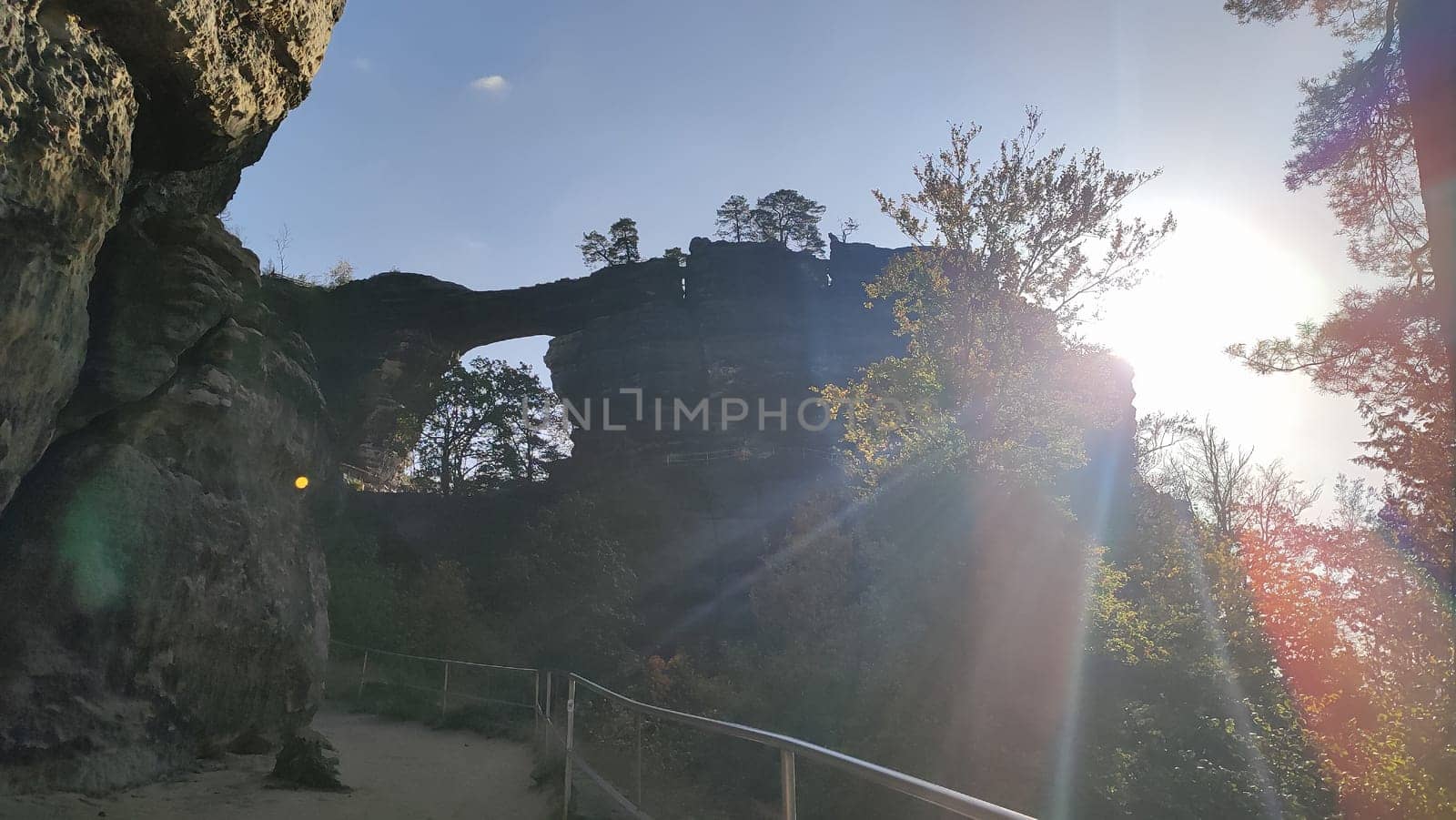 Rocky arch sunlight sun forest green nature blue sky landscape travel tourism summer park . High quality photo