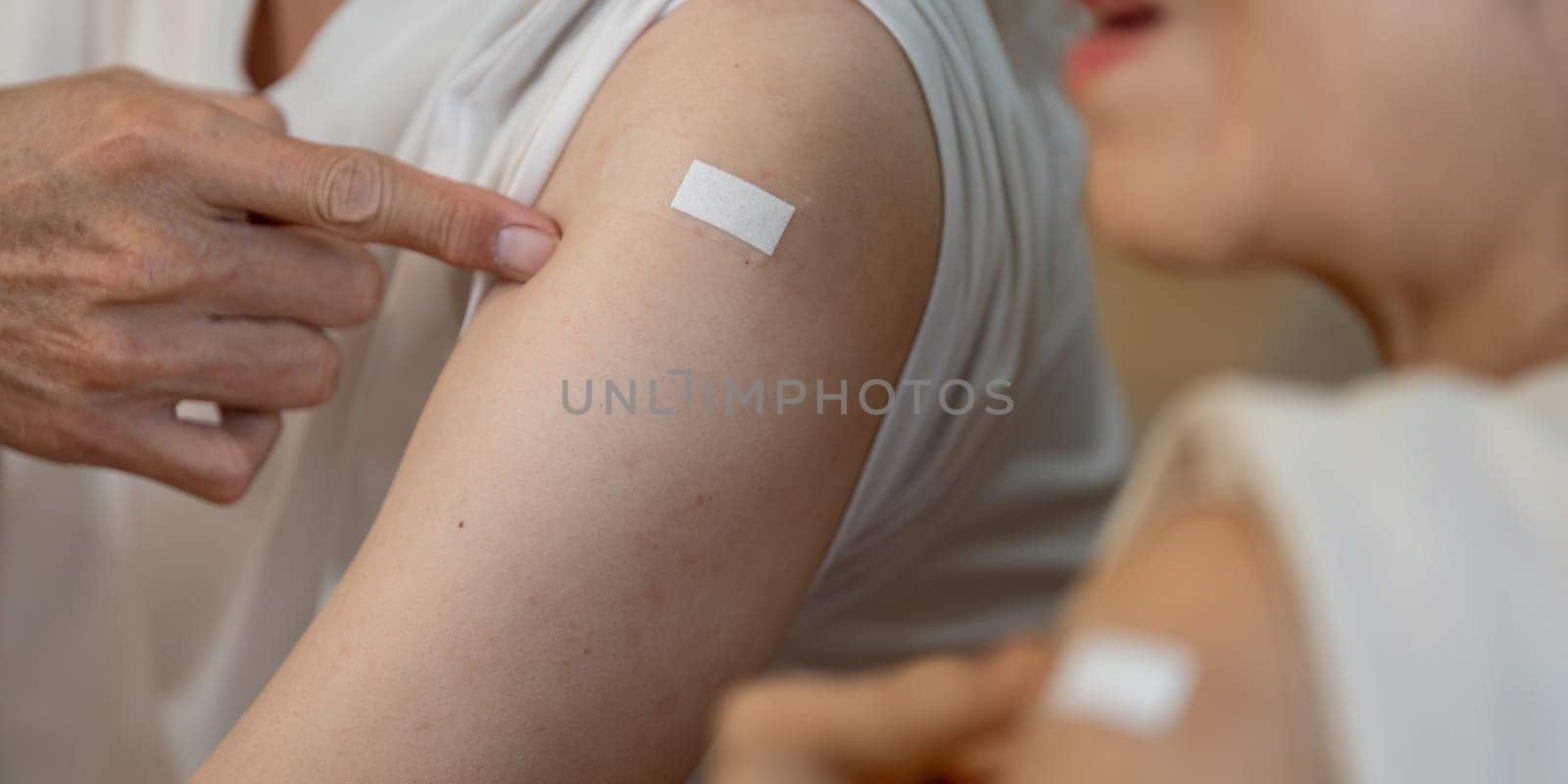 An elderly couple displays their vaccination bandages, smiling and celebrating their health after receiving shots.