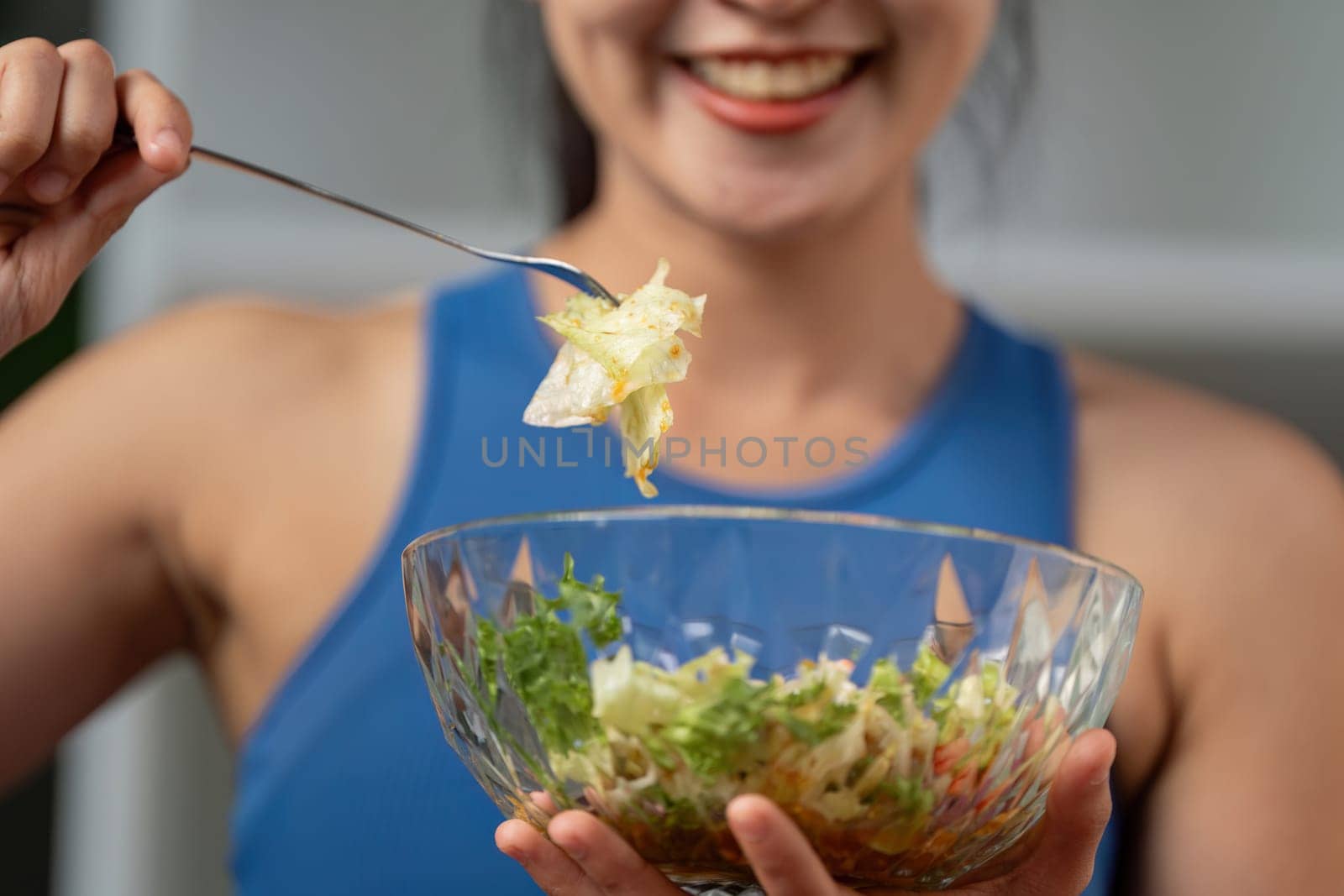 A close-up of a woman joyfully holding a fork with salad, emphasizing healthy eating and vibrant flavors.