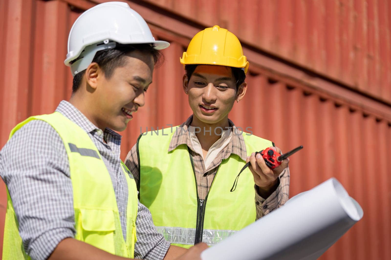 Engineers collaborate on construction logistics, using blueprints and a walkie-talkie for effective communication.