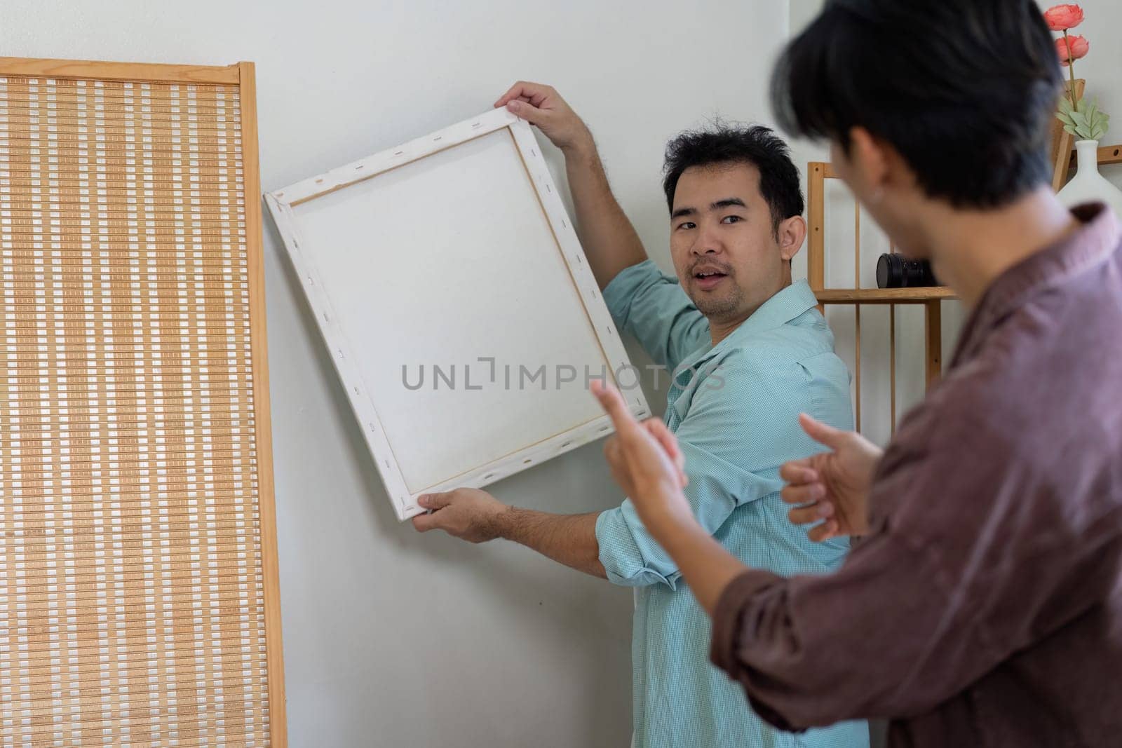 A gay couple works together to decorate their new home, reflecting their shared vision and teamwork.