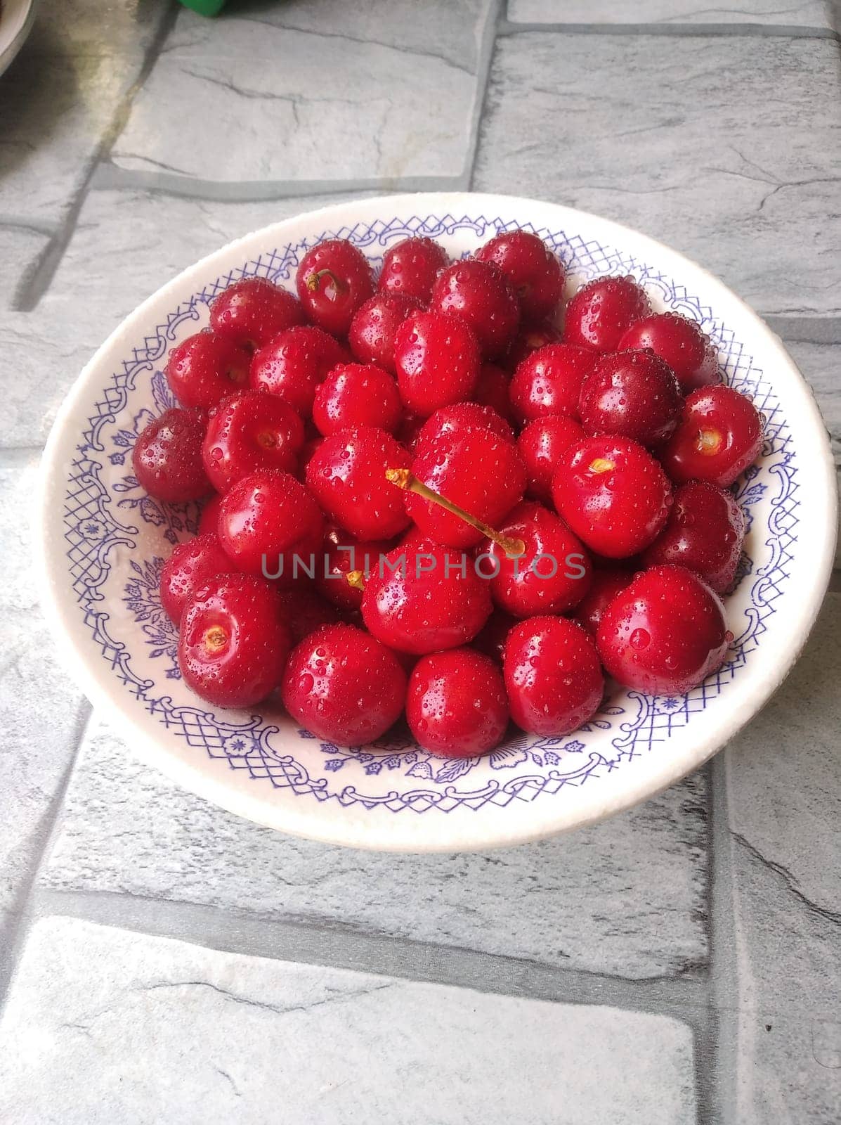 ripe juicy red cherry on a plate covered with droplets of moisture