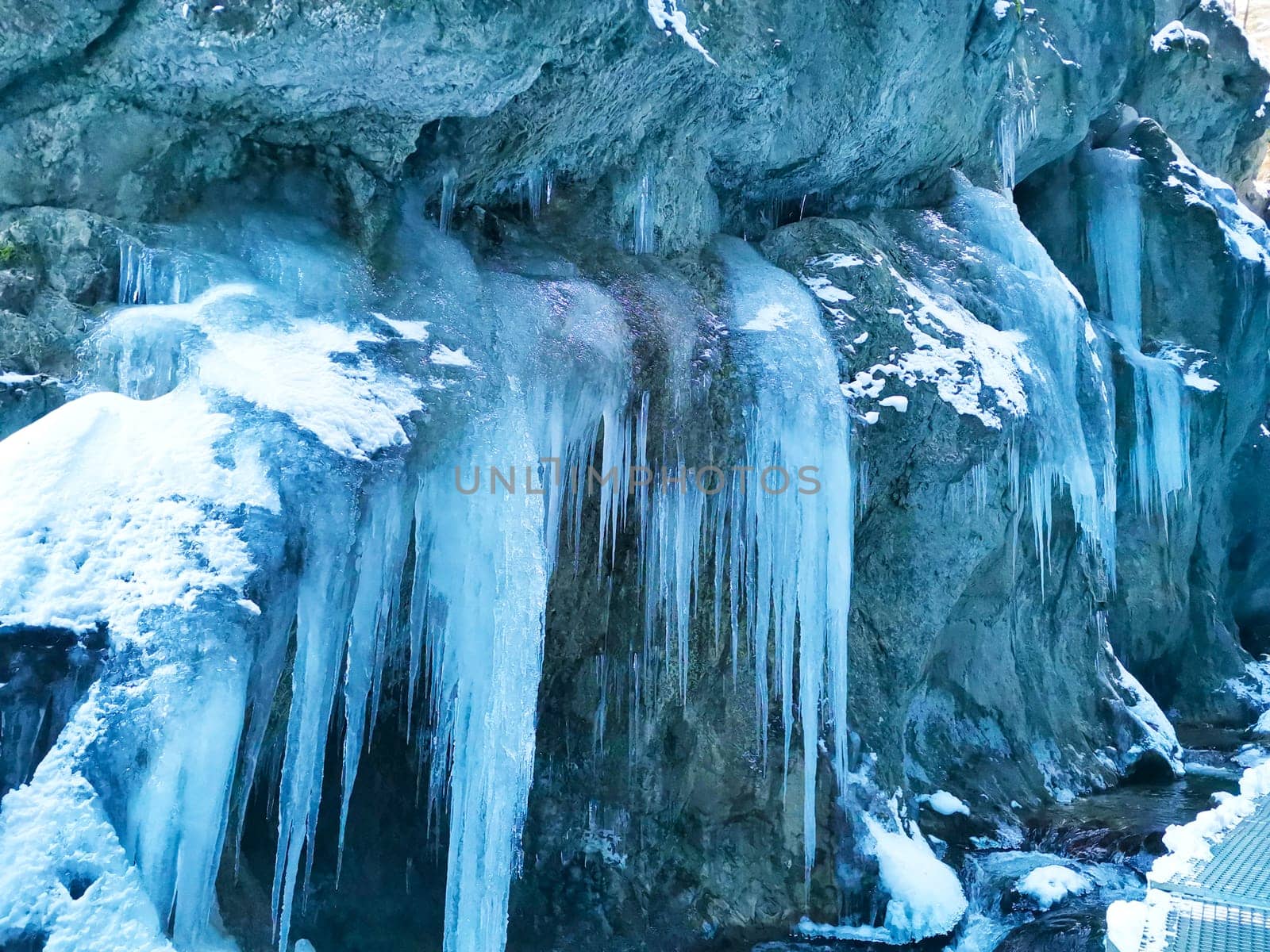 Huge icicles hang from steep cliff. Beauty in nature. Winter landscape with frozen water