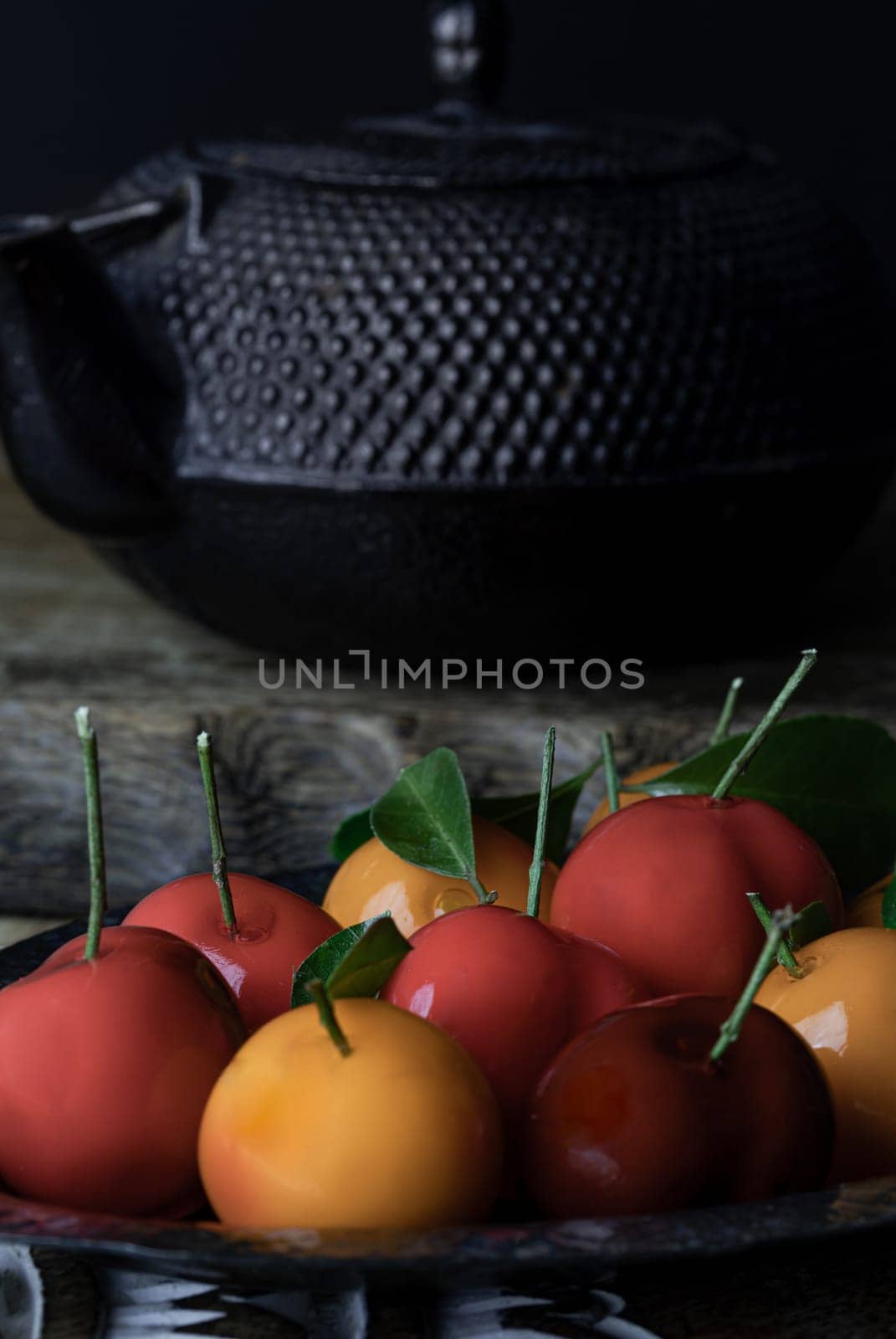 Colorful deletable imitation fruits (Kanom look choup) in the shape of oranges, rose apple and strawberries has a sweet taste. Traditional thai sweet treats made from mung beans and coconut milk, and glazed in shiny agar agar jelly, Auspicious thai dessert, use it as your Wallpaper, Poster and Space for text, Selective focus.