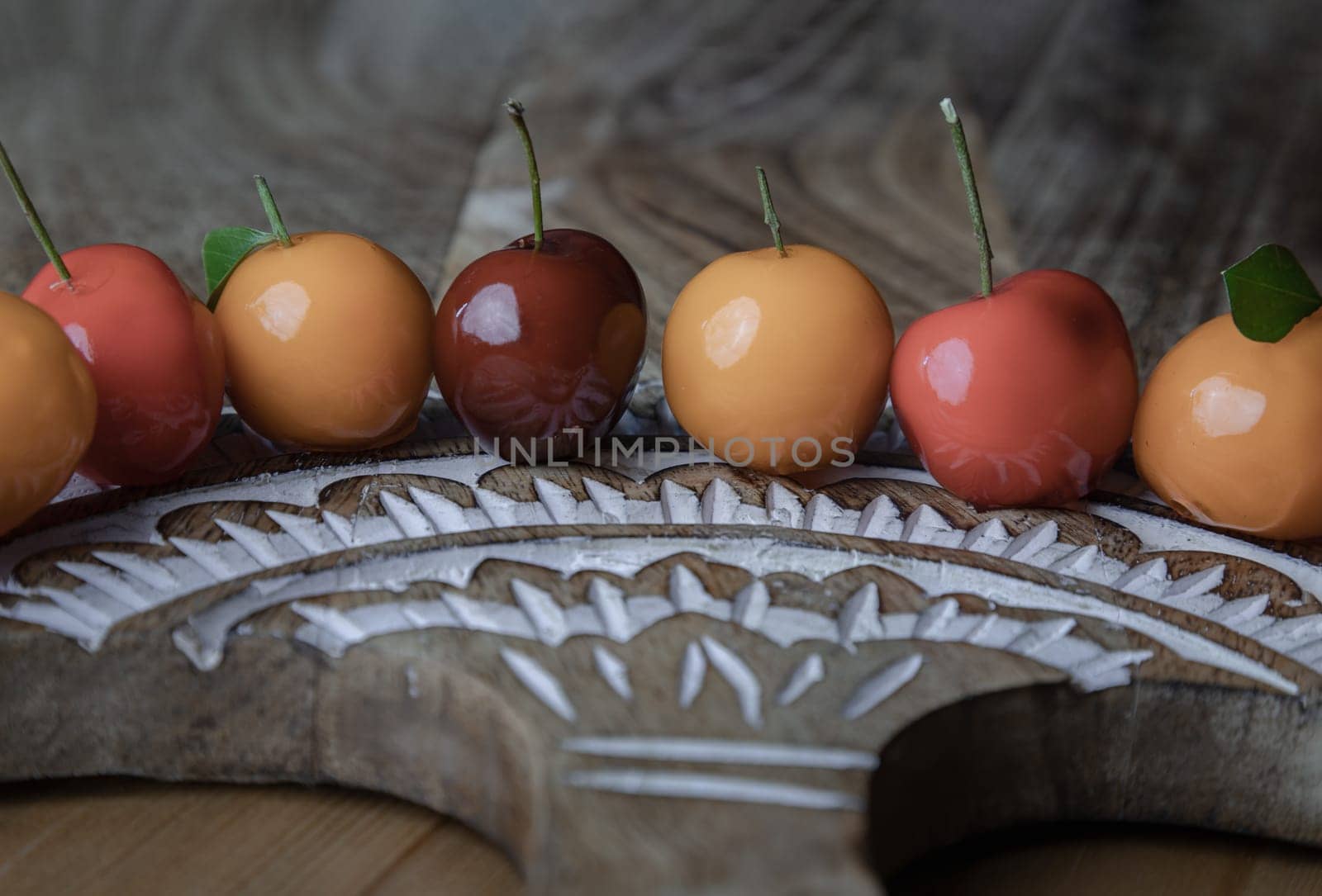 View of Deletable imitation fruits (Kanom look choup) in the shape of fruits has a sweet taste on wood cutting board. Traditional thai sweet treats made from mung beans and coconut milk, and glazed in shiny agar agar jelly, Auspicious thai dessert, use it as your Wallpaper, Poster and Copy space, Selective focus.