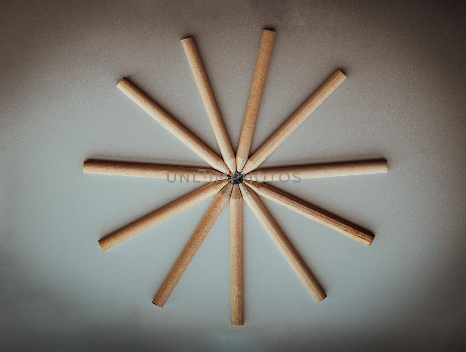 Top view of Brown crayons arranged in a circle on silver background. Wooden colored pencils come together and circle, An artistic display of colored pencils, Stationery for drawing, Minimalism art supplies dark concept, Empty space for text, design and wallpaper, Selective focus.