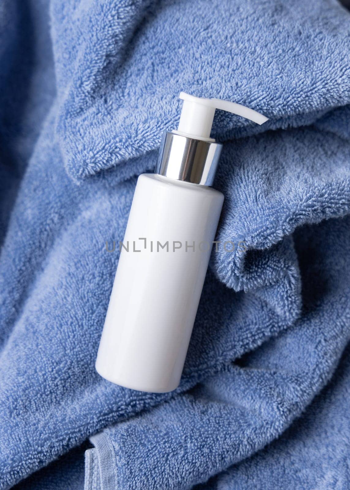 White blank one pump bottle on blue towel in bathroom closeuptop view, brand packaging mockup. Natural handmade cosmetic product - cream, lotion or soap for daily face or handcare, copy space