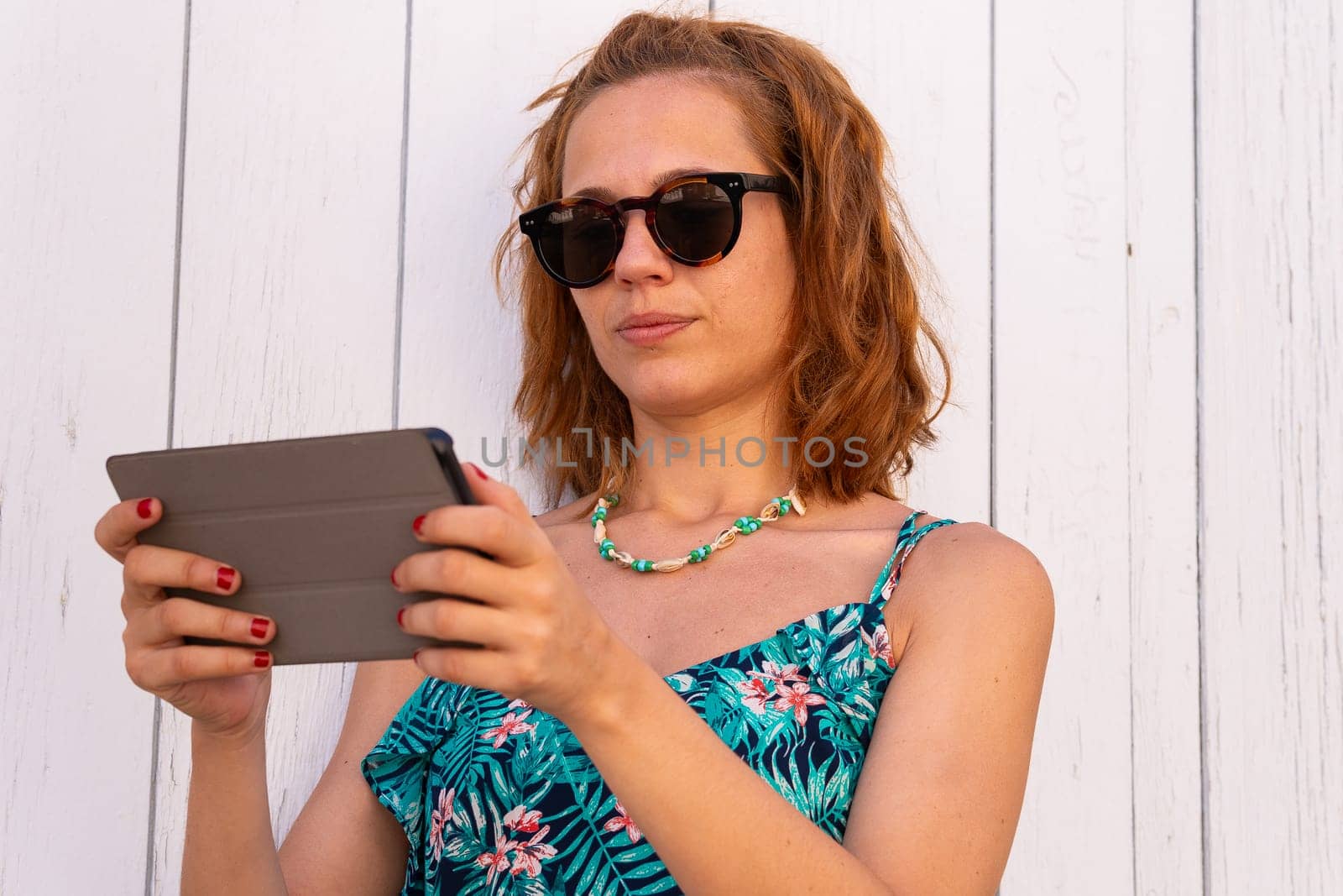 Portrait of a smiling young woman with sunglasses and digital tablet in hands.