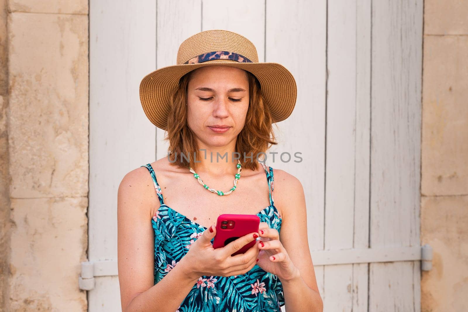 Portrait of a smiling young woman wearing a hat using a social media app