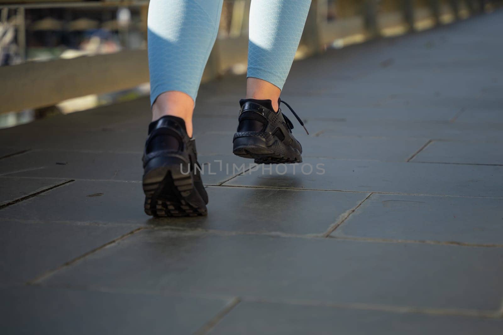 Feet of a sporty woman running through the streets of the city.