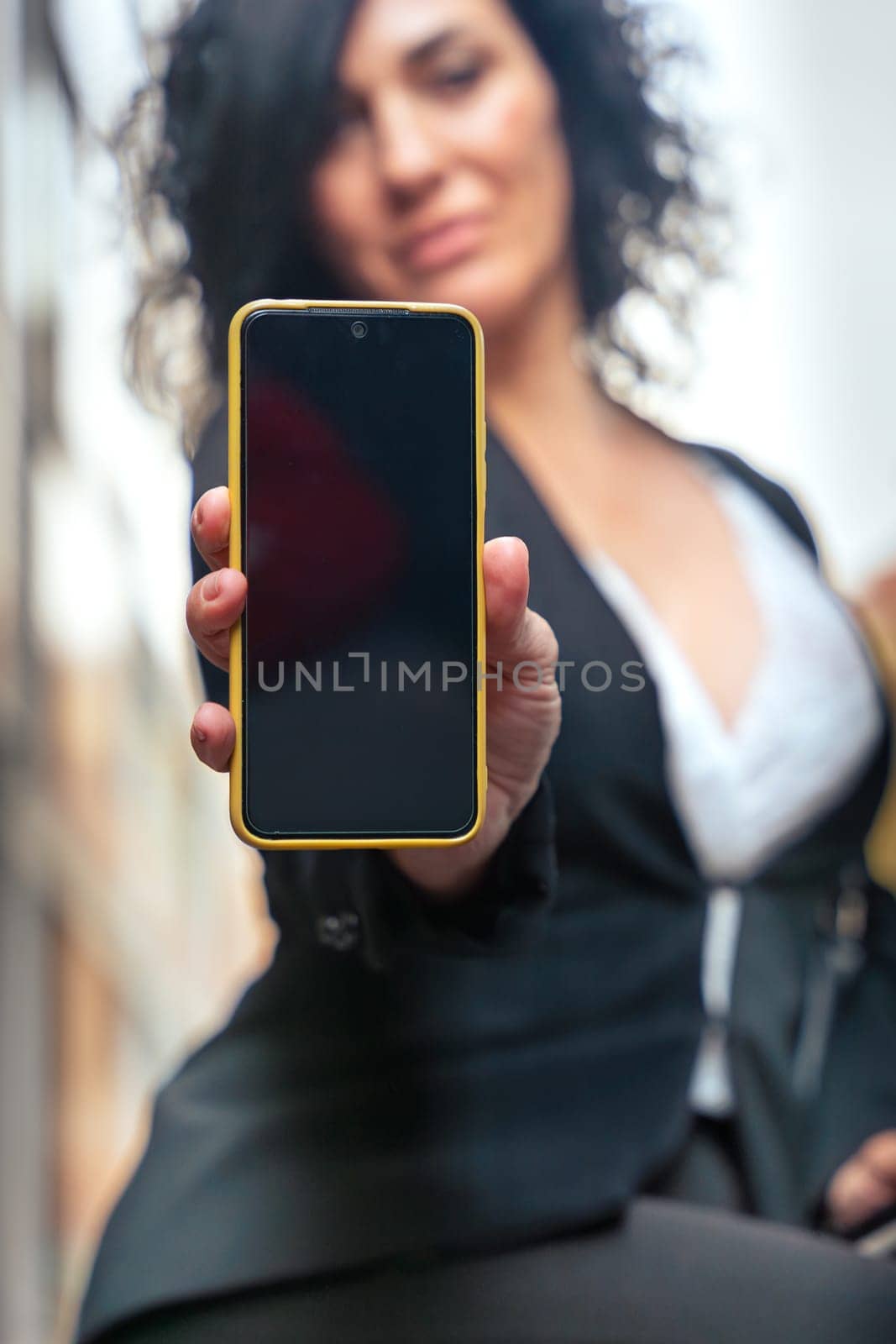 woman shows a smartphone with an empty screen for advertising or presentation, look at camera., smiling. Gadget Concept