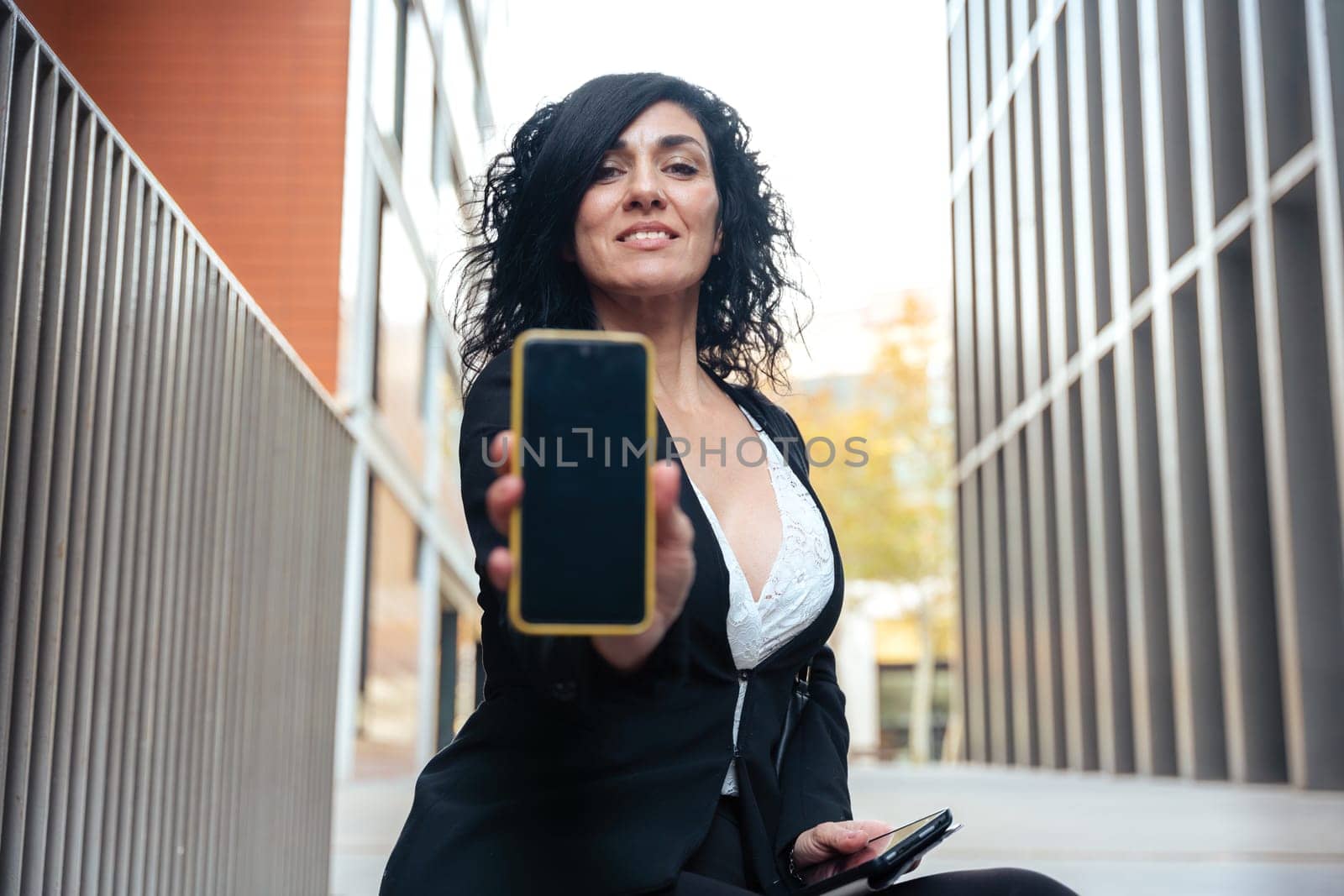 woman shows a smartphone with an empty screen for advertising or presentation, look at camera., smiling. Gadget Concept