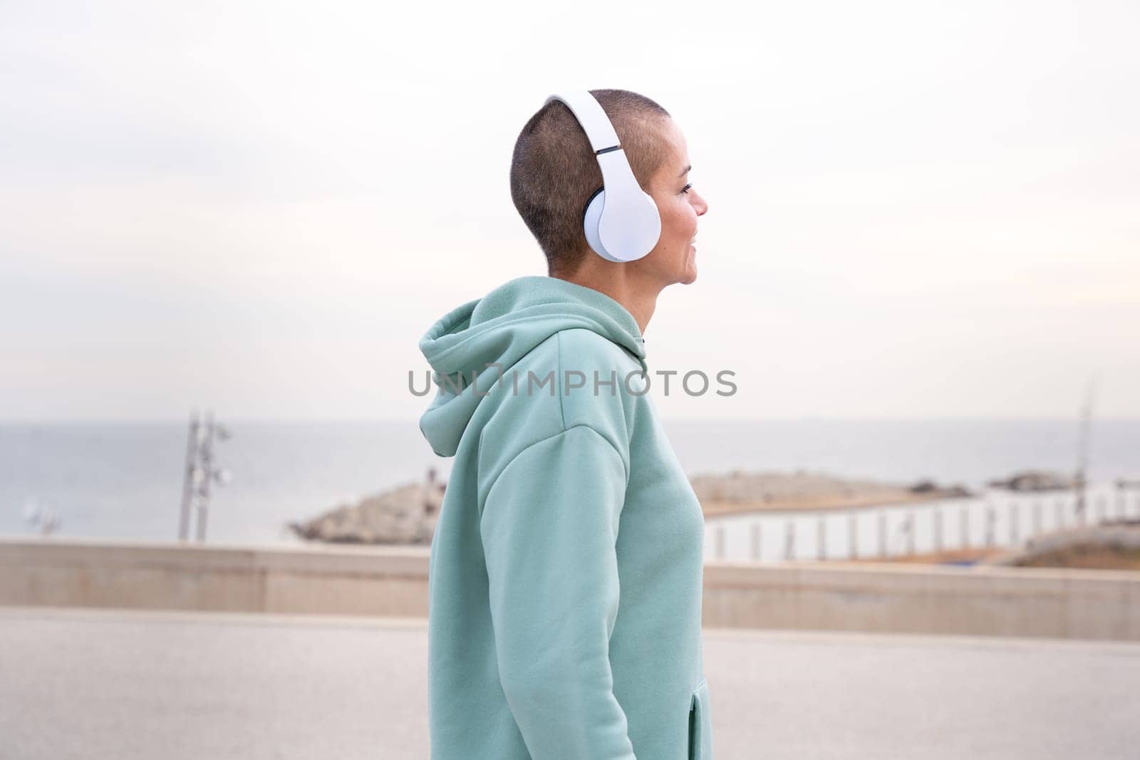 Portrait Fit caucasian woman smiling at camera with headphones on. Woman having fun during her morning workout.