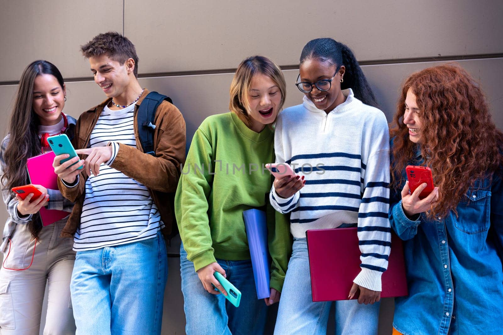 Five multiracial friends having fun using social media with their smartphone on the university campus. University life concept.
