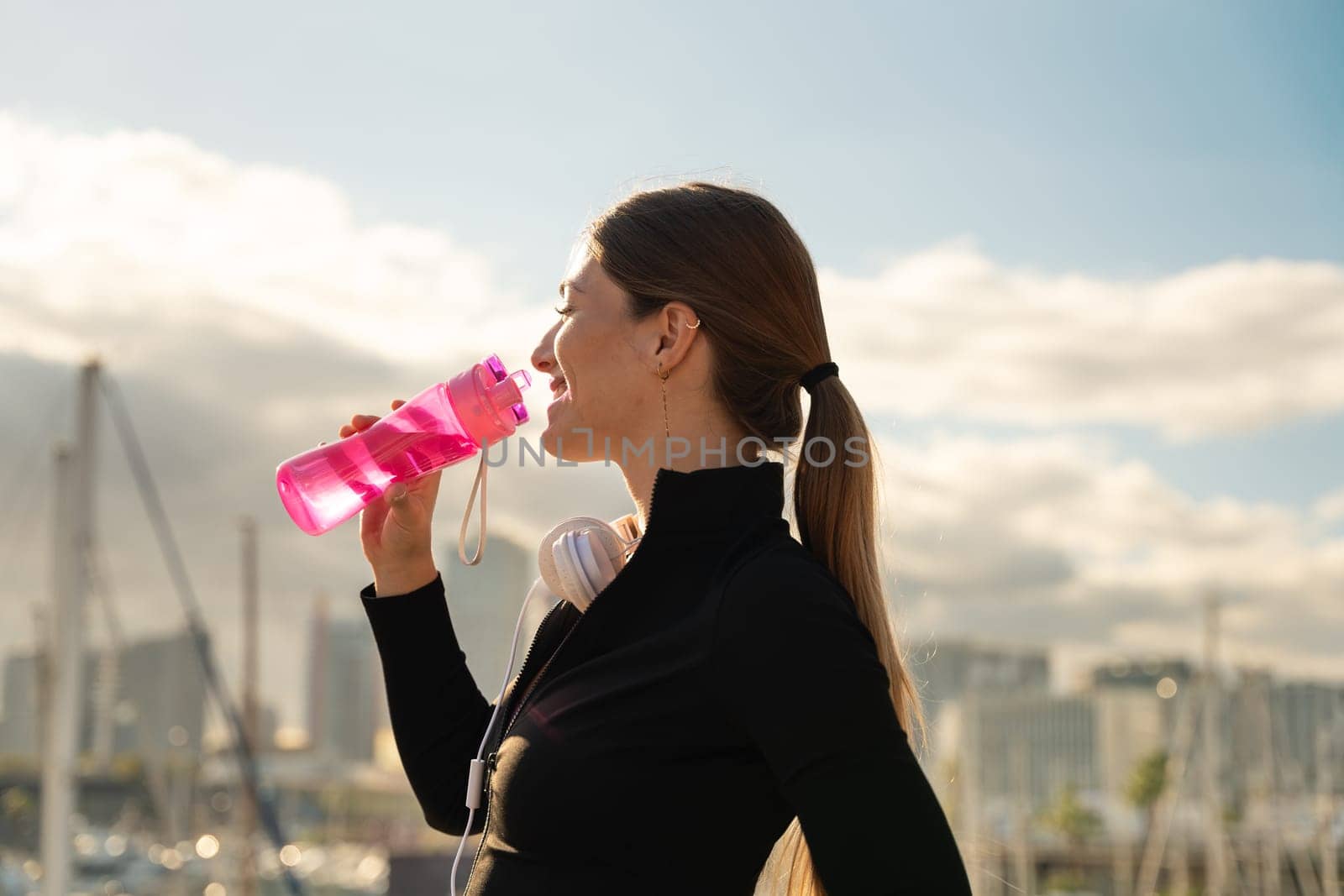 athletic woman smiling drinking water while exercising