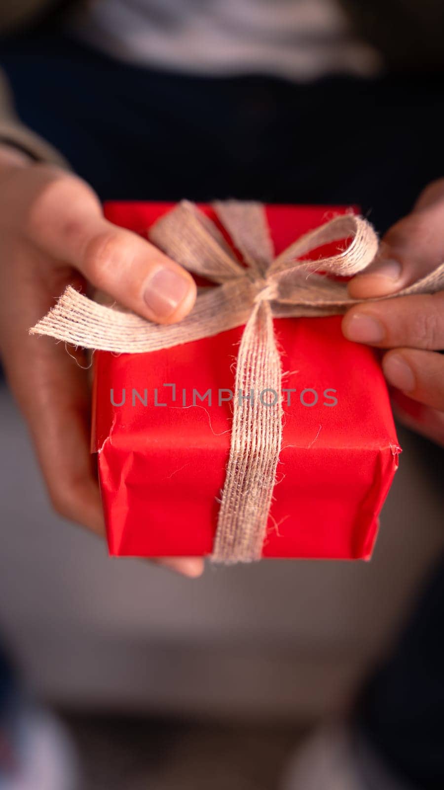 Elegant man holding gift with ribbon on the sofa at home.Celebrating Valentine's Day