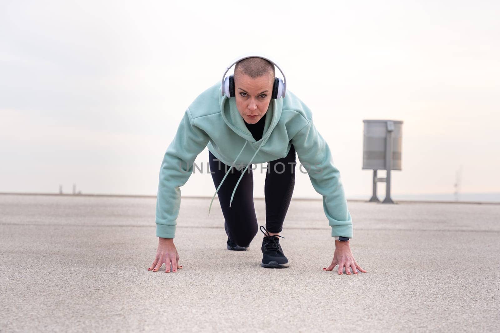 Concentrated young woman with sports headphones ready to start running.
