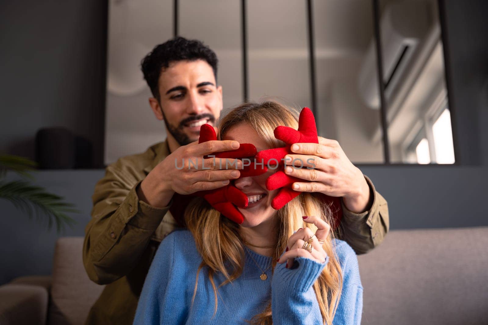 Smiling young man covers his girlfriend's eyes with a giant heart. Lovers