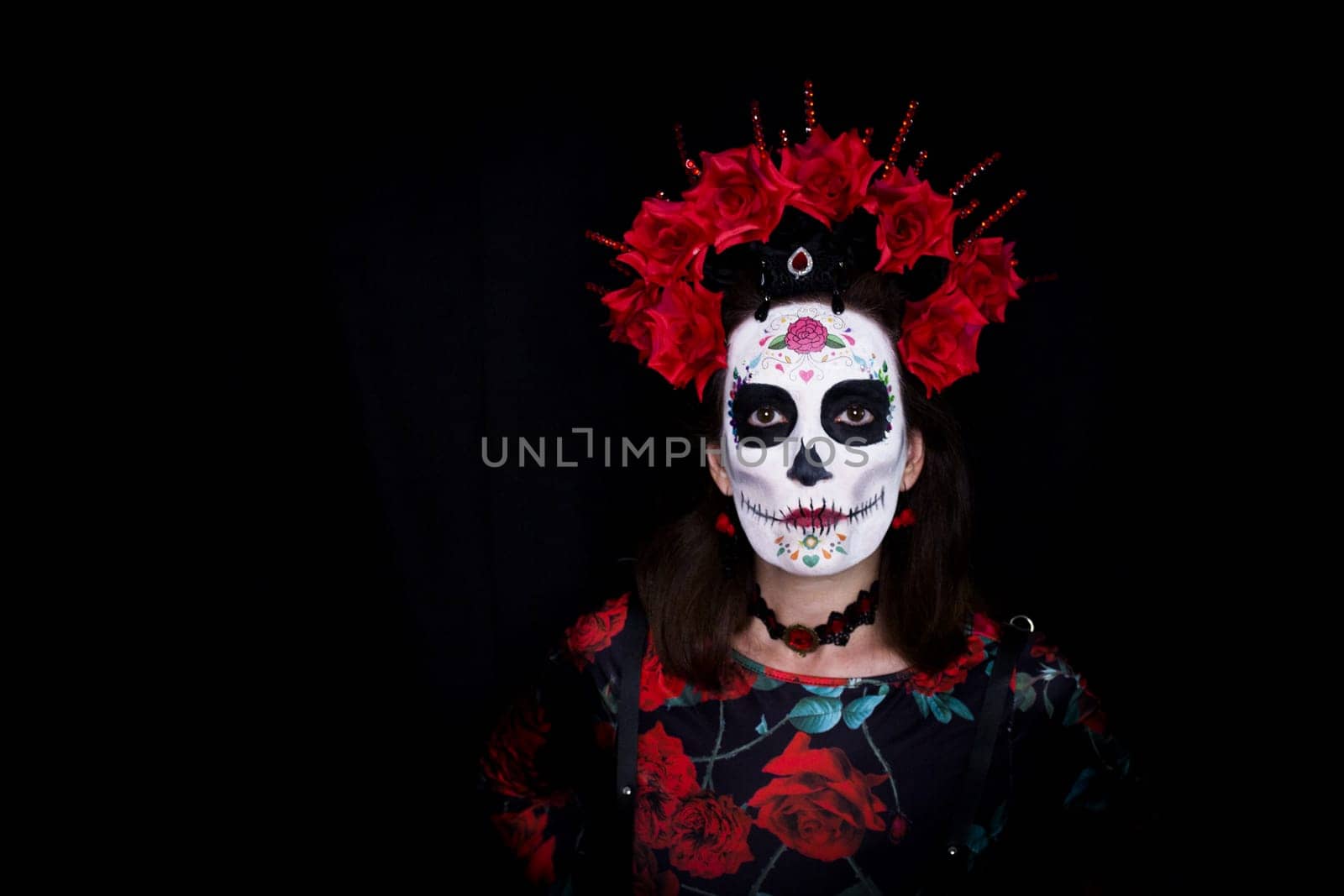 Woman dressed as a Mexican Catrina with a crown of red and black flowers