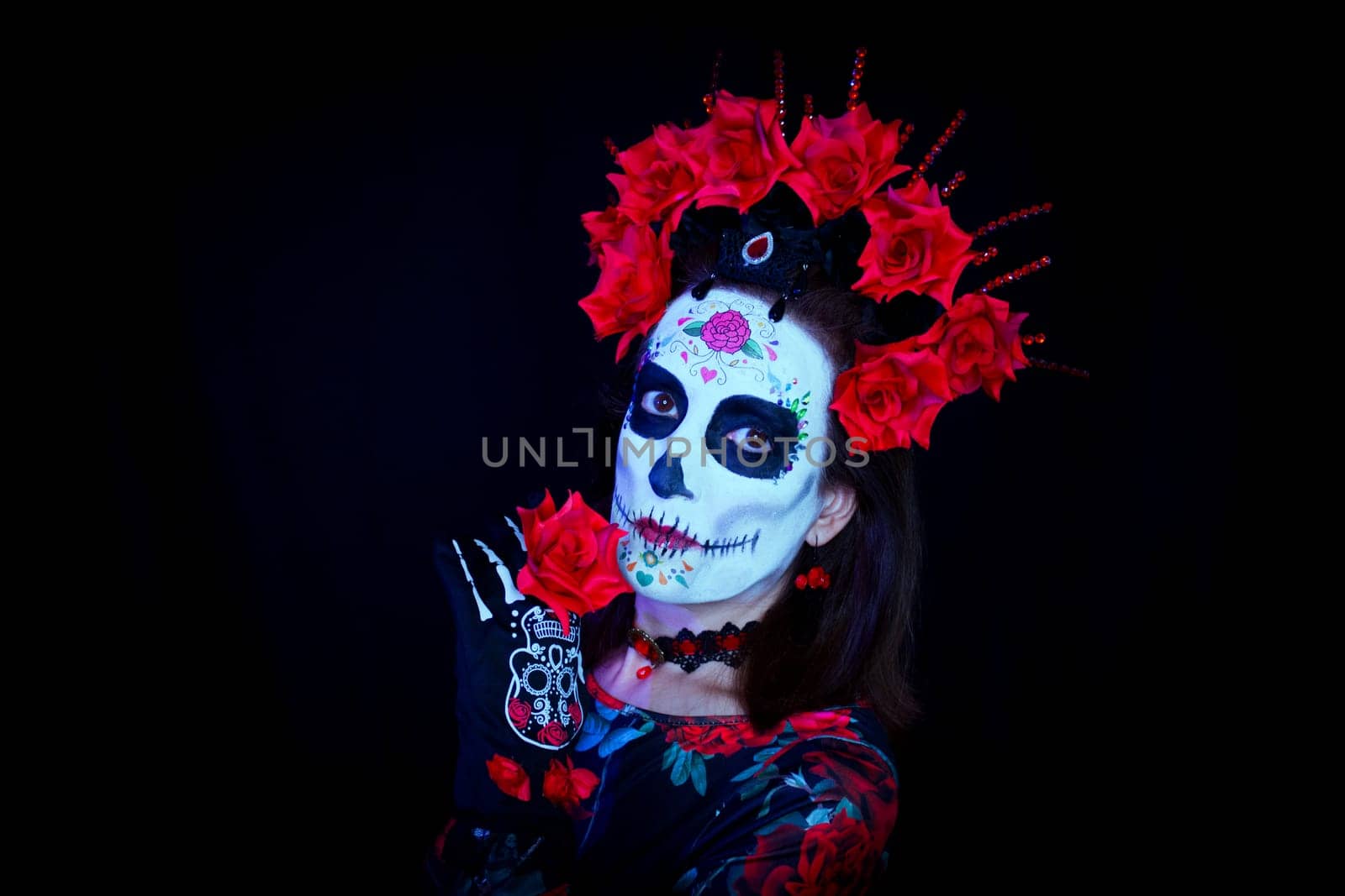 Woman dressed as a Mexican Catrina with a crown of red and black flowers