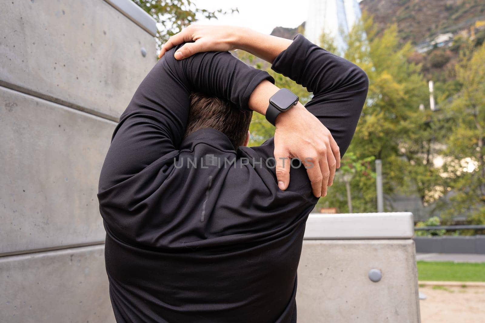 Active and fit male runner doing stretching exercises before running or doing cardio exercise.