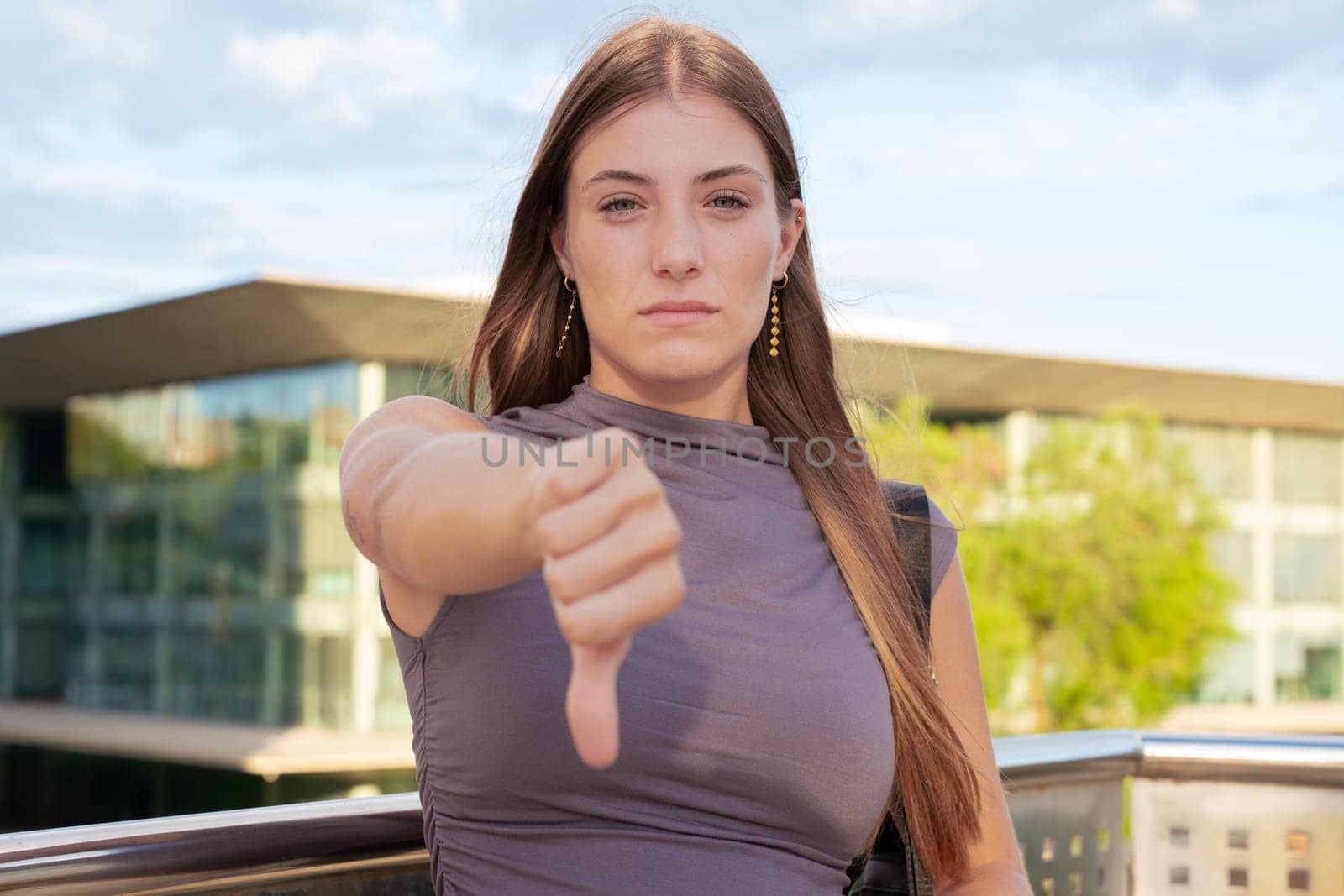 Close-up of pensive teenage female student pointing thumbs down.confident facial expression.