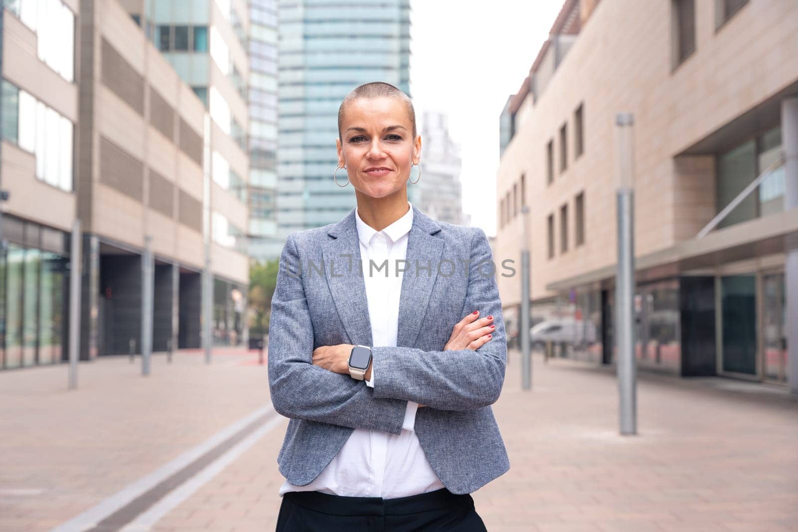 Close-up of a caucasian businesswoman looking happy at the camera in a suit standing in outdoor workspace. Front view of a young lawyer with thoughtful expression staring