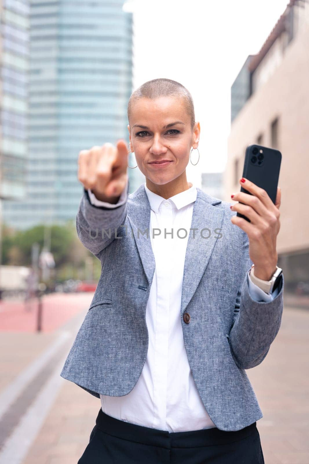 Confident middle adult pointing finger to front of logo. Smiling young woman pointing finger towards camera.