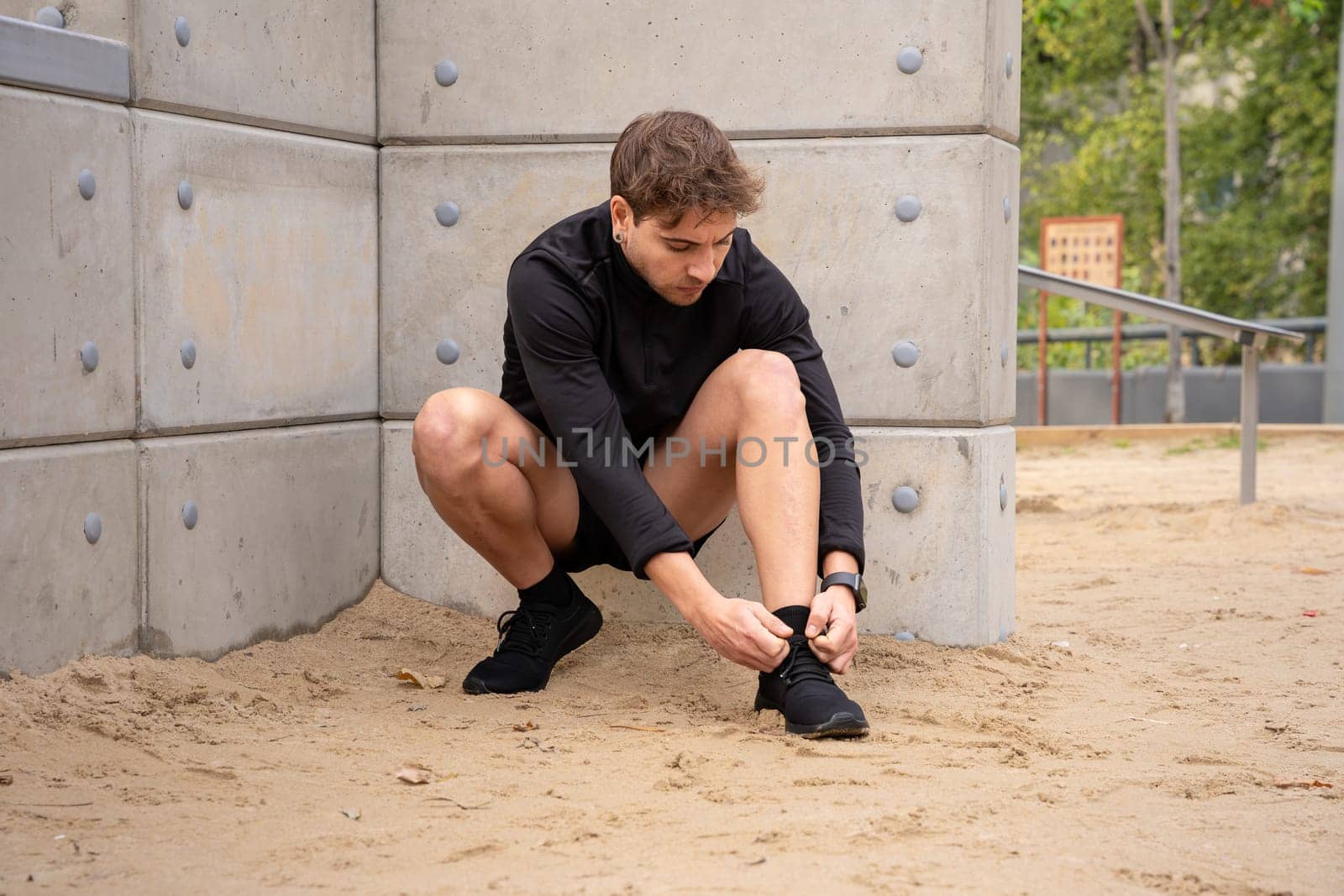 Man tie the lace on his shoes to start running and exercise. Runner tying running sneakers on the side walk or pavement of the road, getting ready to go for a run. Fitness, training and cardio