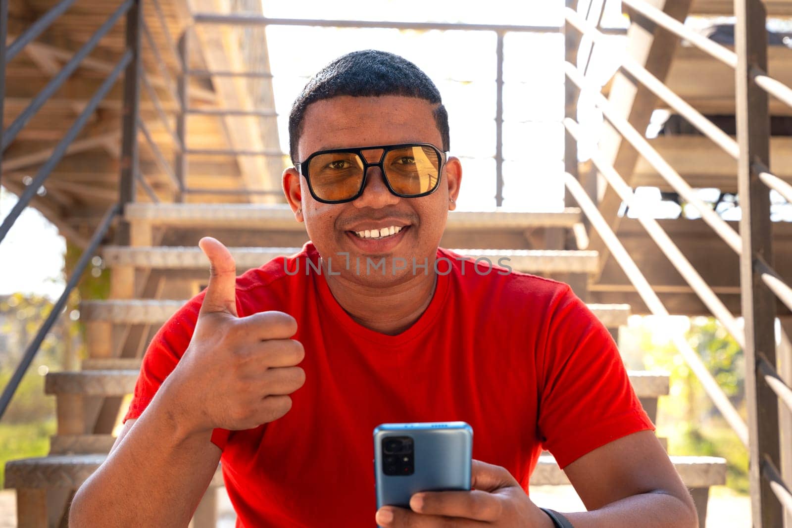Closeup of a young latin man pointing thumb up. Confident facial expression.
