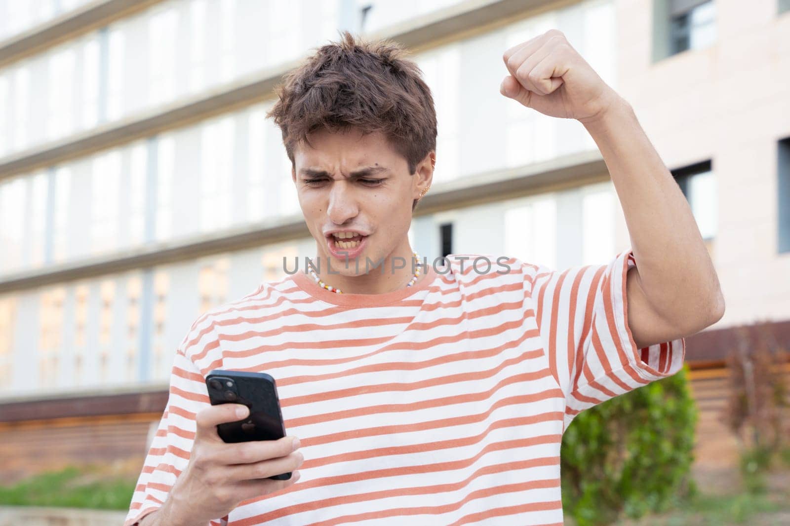 Excited caucasian man using mobile phone watching football match. Student euphoric about the exam result.