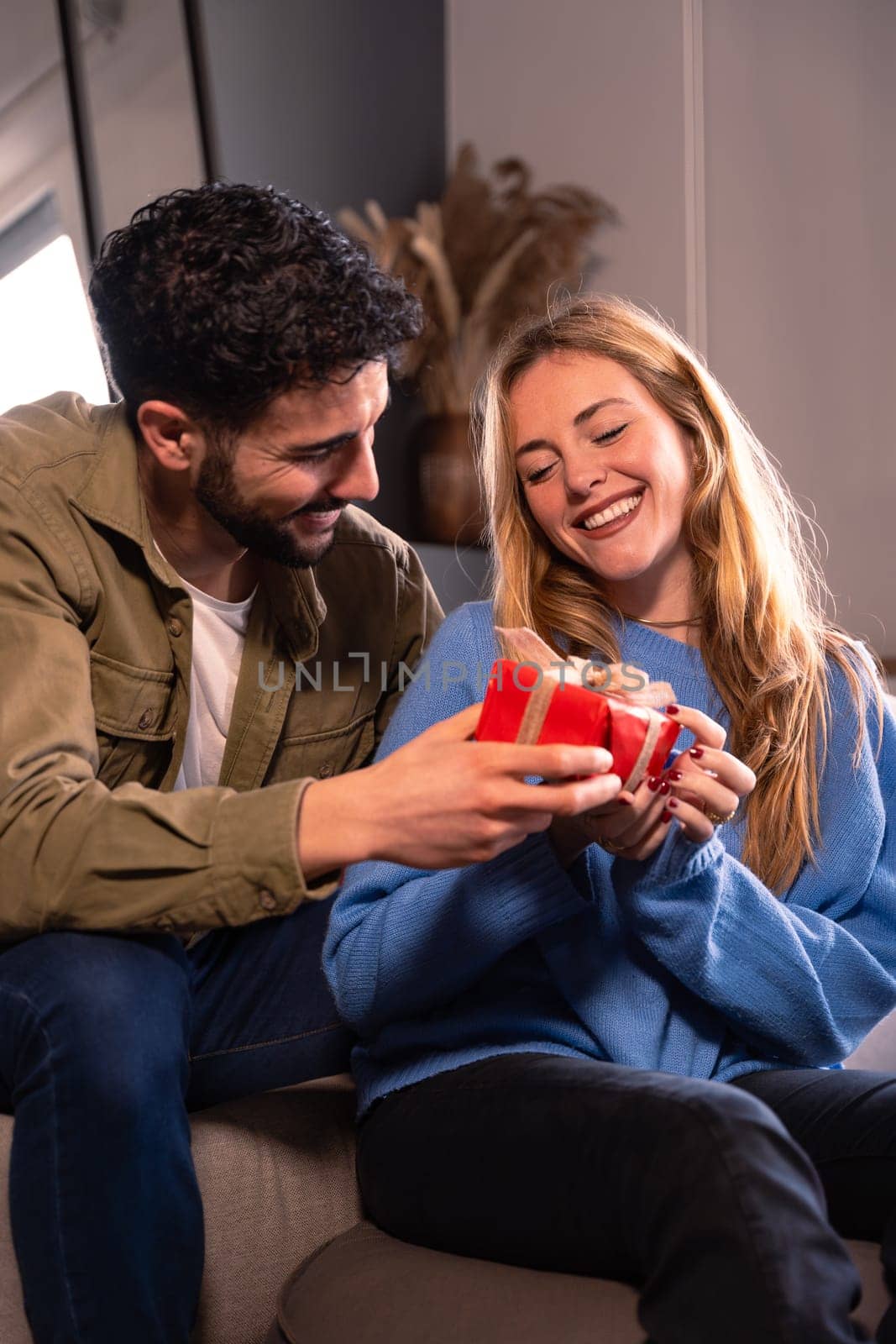 happy and smiling young man and woman hugging and holding red gift box.Lovers